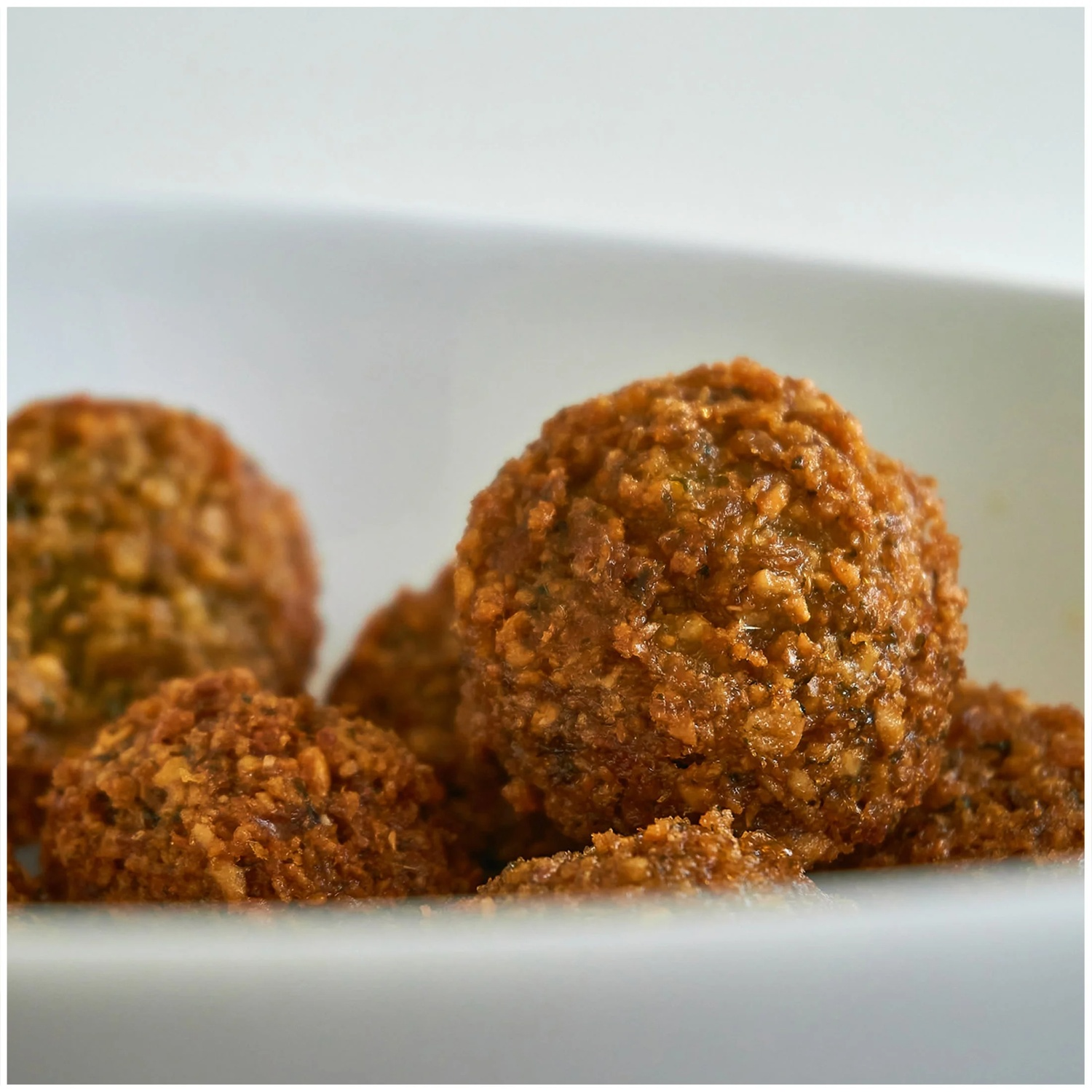 Boules de falafel dorées et frites dans un bol blanc.