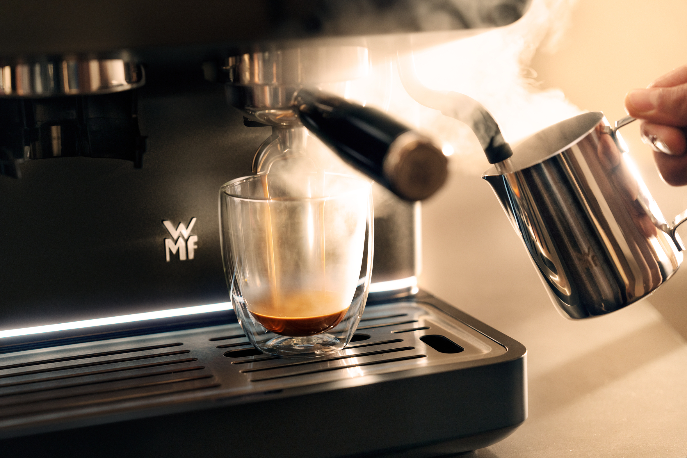 Máquina de espresso preparando café en un vaso mientras se espuma leche.