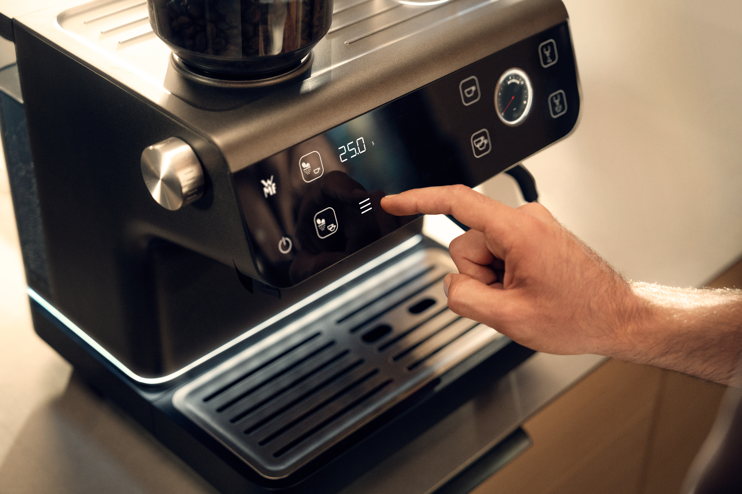 Una mano opera una cafetera con pantalla digital y dial.