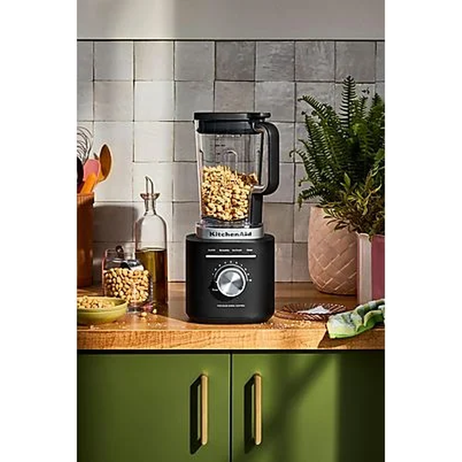 A black blender with nuts in the container sits on a countertop.