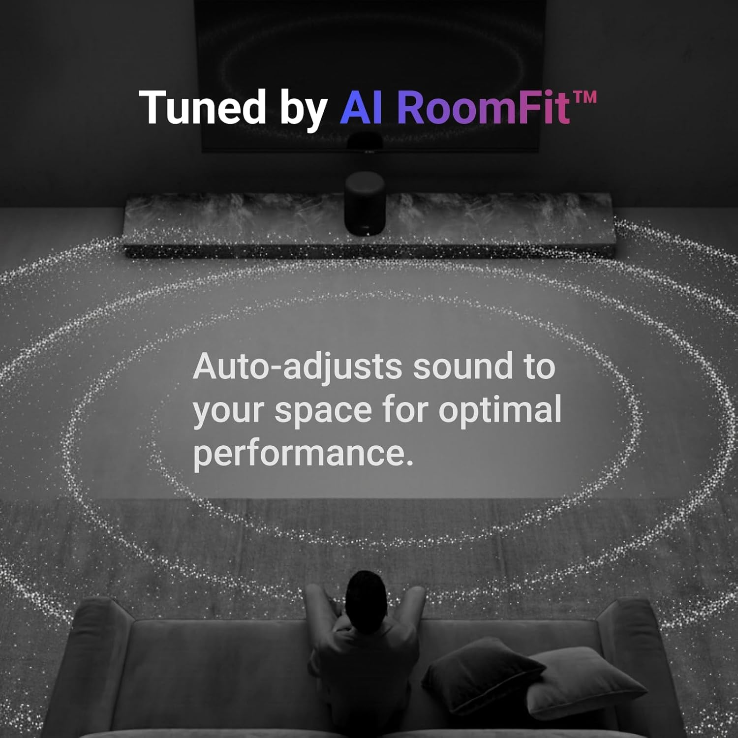 Ein Mann sitzt auf einer Couch vor einem Fernseher, der mit AI RoomFit™ abgestimmt ist.