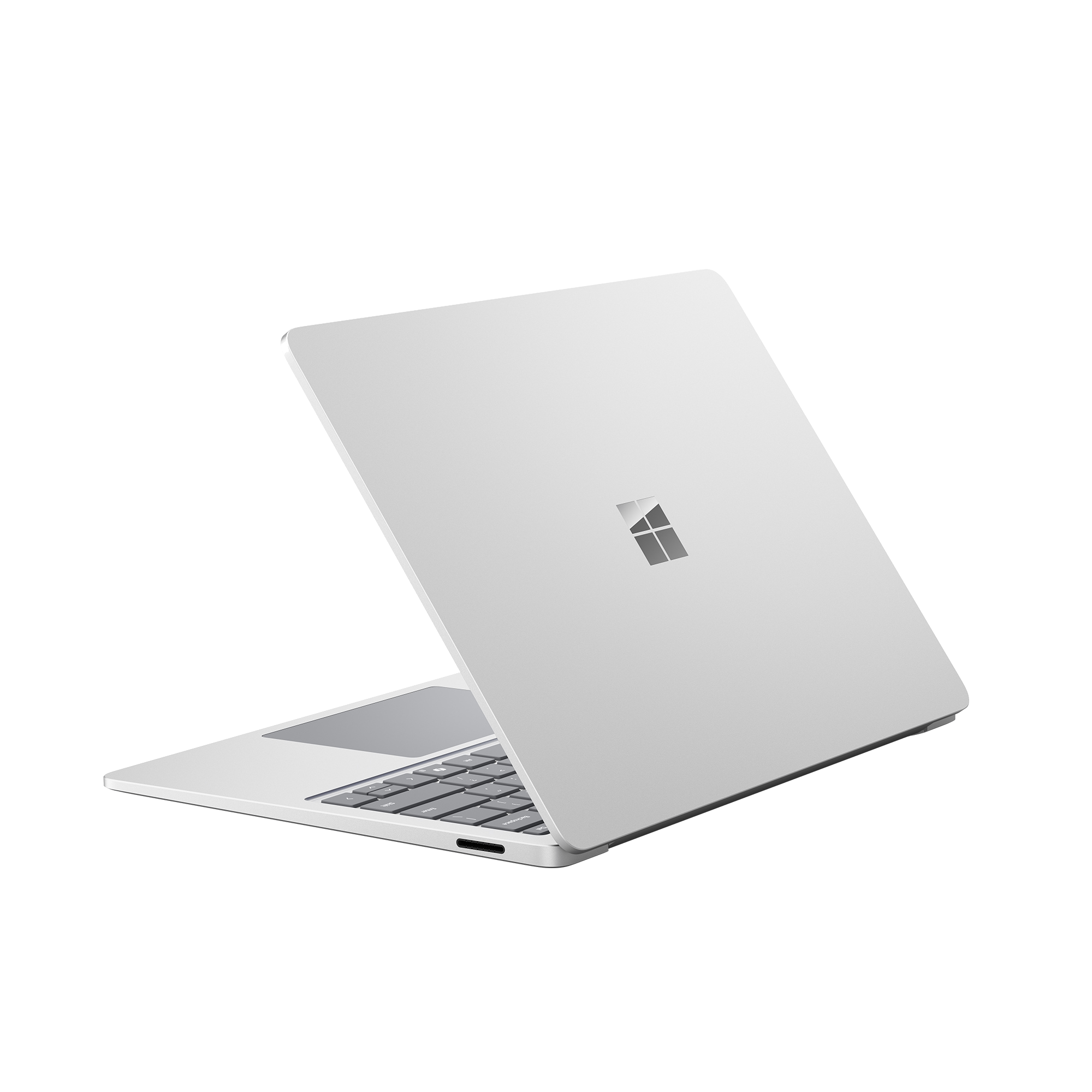 Un portátil plateado con la pantalla abierta, mostrando el teclado y el logo de Microsoft.