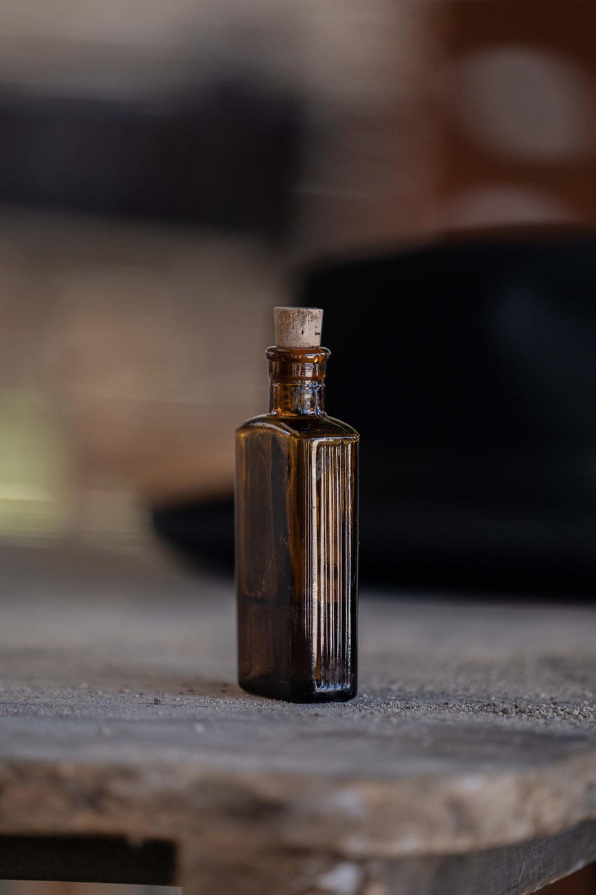 Eine kleine braune Glasflasche mit Korkenverschluss steht auf einer Holzoberfläche.