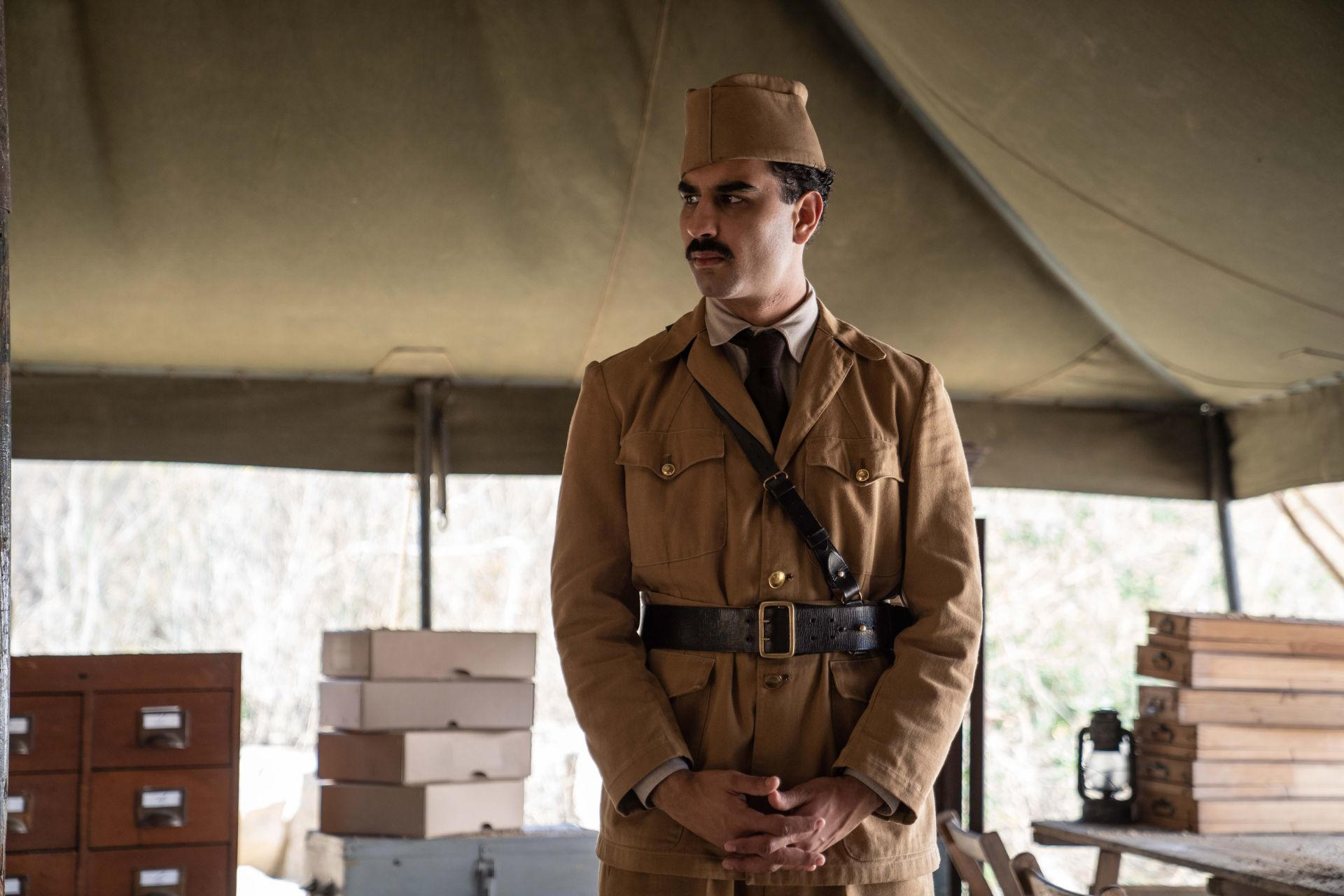 Mann in Uniform mit Hut und Bandelier unter einem Zelt.