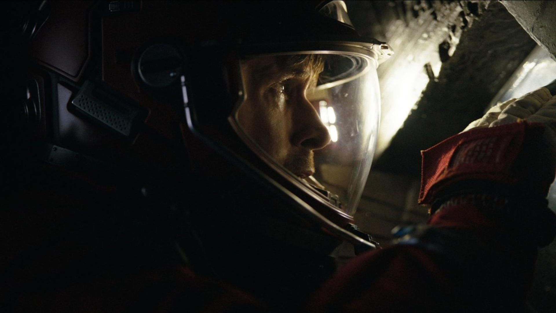 Ein Astronaut im Helm blickt nach rechts in einer dunklen Umgebung.