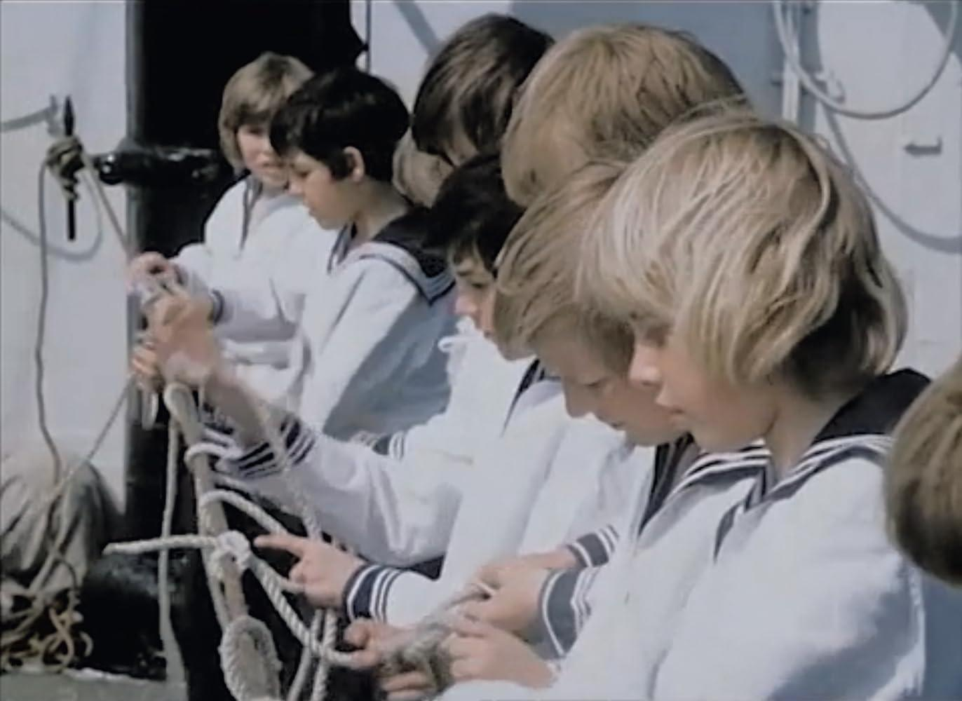 Jungen in Matrosenuniformen knoten Seile auf einem Schiff.
