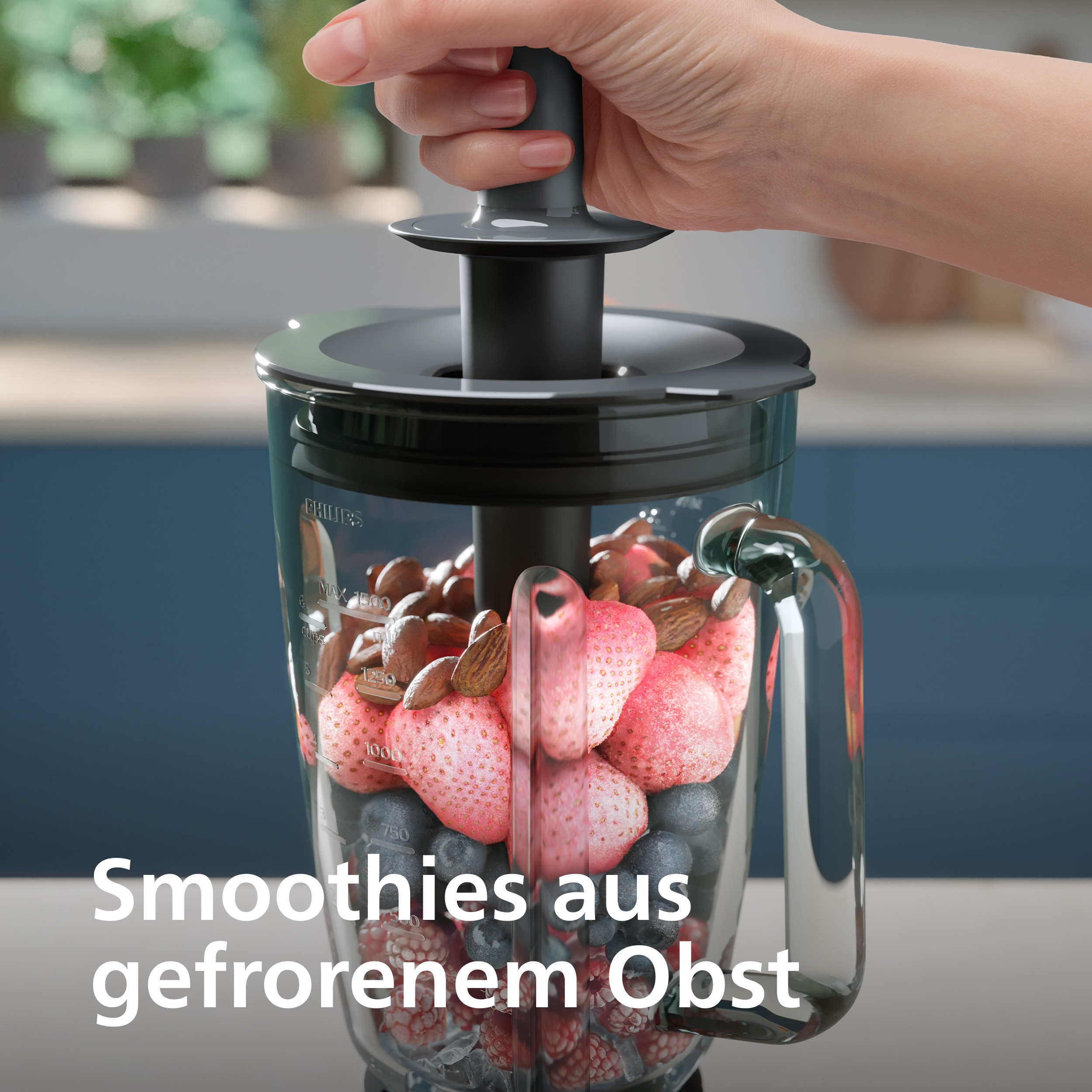 Hand betätigt Mixer mit Erdbeeren, Blaubeeren, Himbeeren und Mandeln.