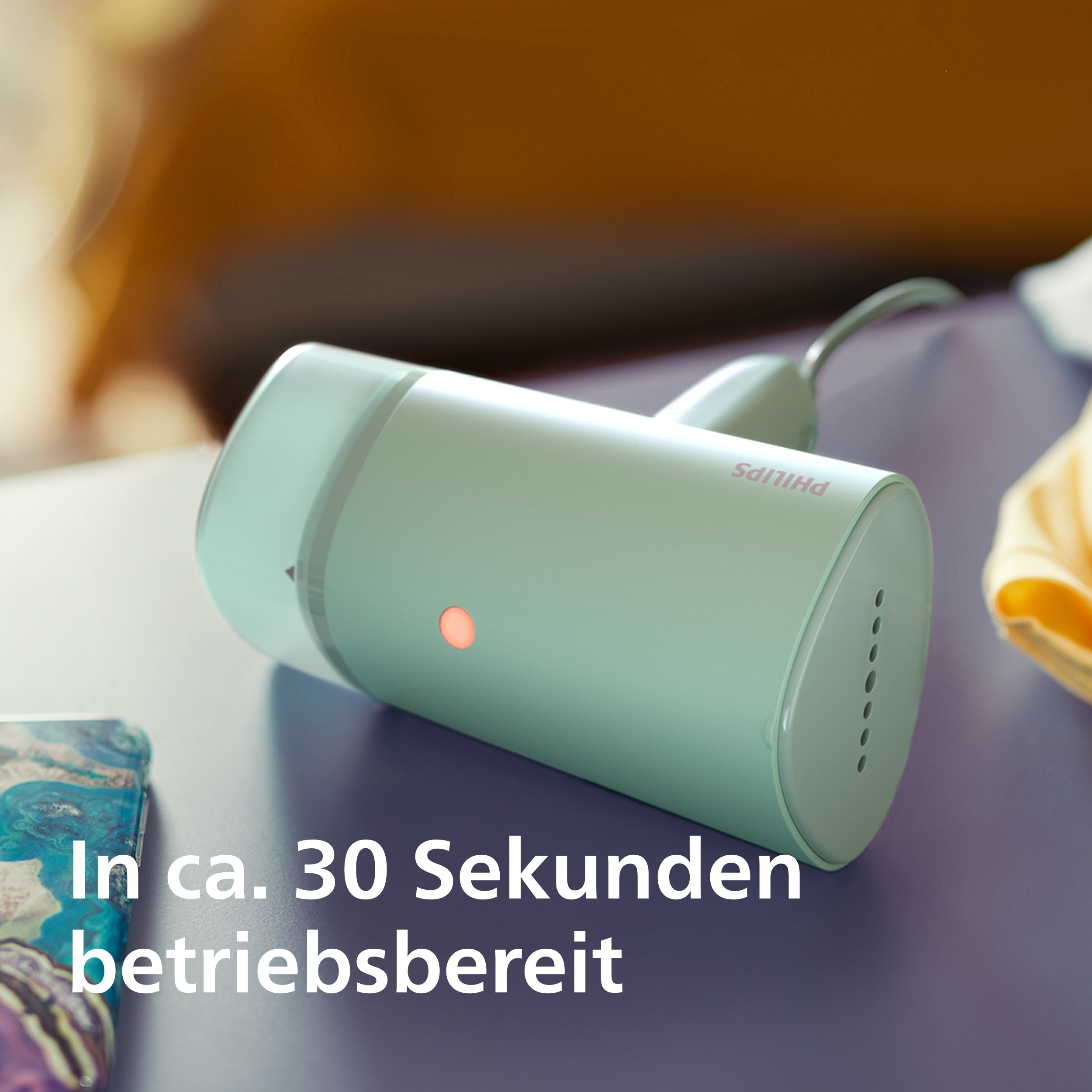 Ein türkisfarbener Philips Handdampfer mit rotem Licht auf einer lila Fläche.