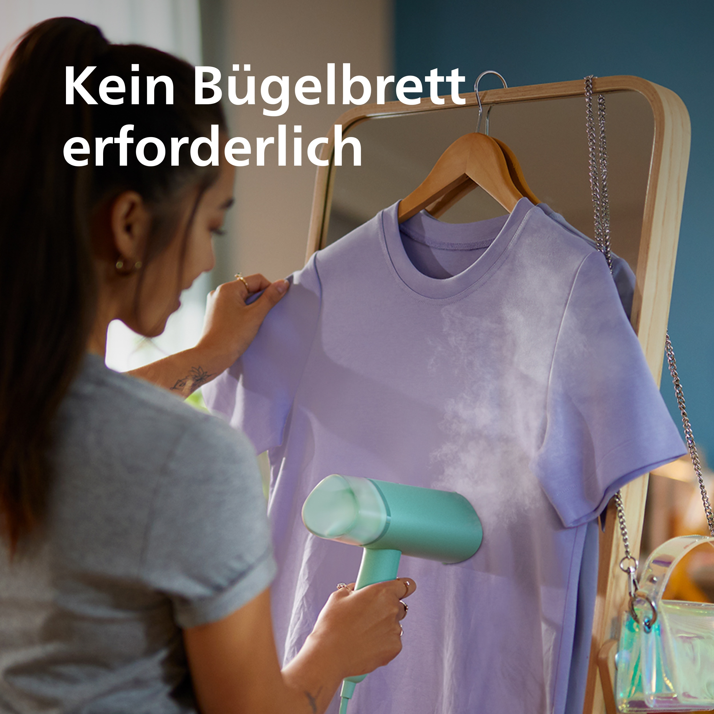 Eine Frau glättet ein lila T-Shirt mit einem Handdampfer.