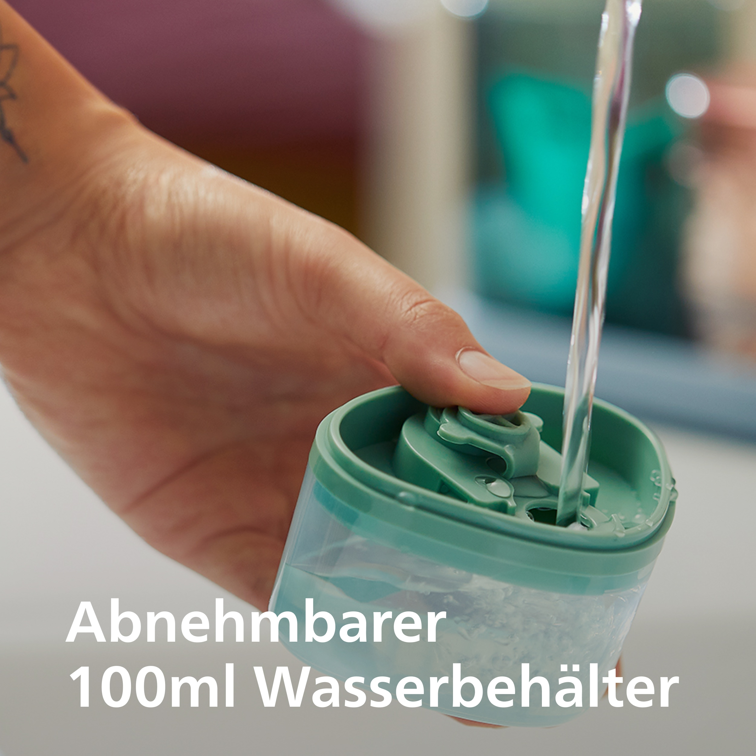 Wasser fließt in einen 100ml abnehmbaren Behälter, der von einer Hand gehalten wird.