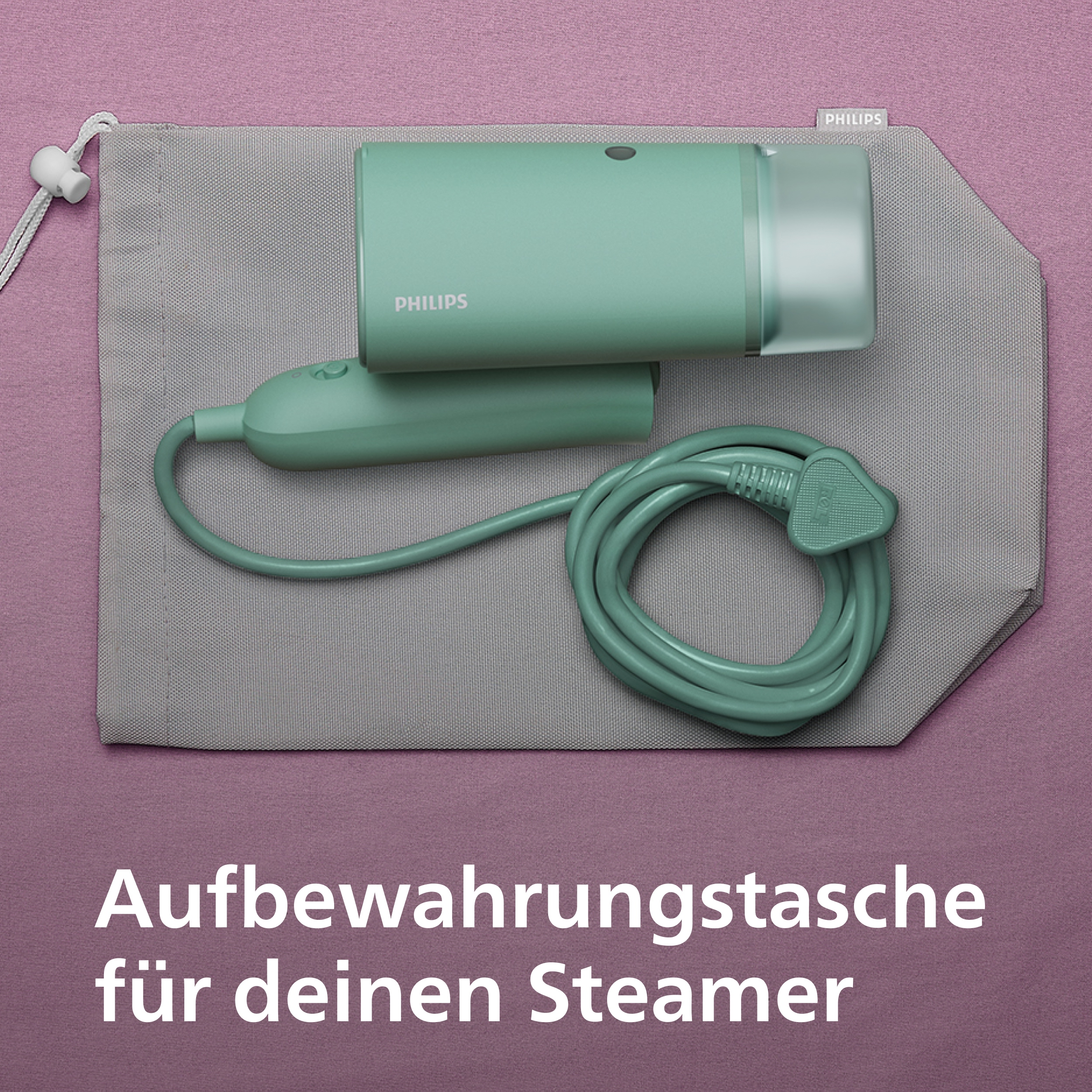 Ein türkisfarbener Steamer mit Kabel und Aufbewahrungstasche auf lila Untergrund.