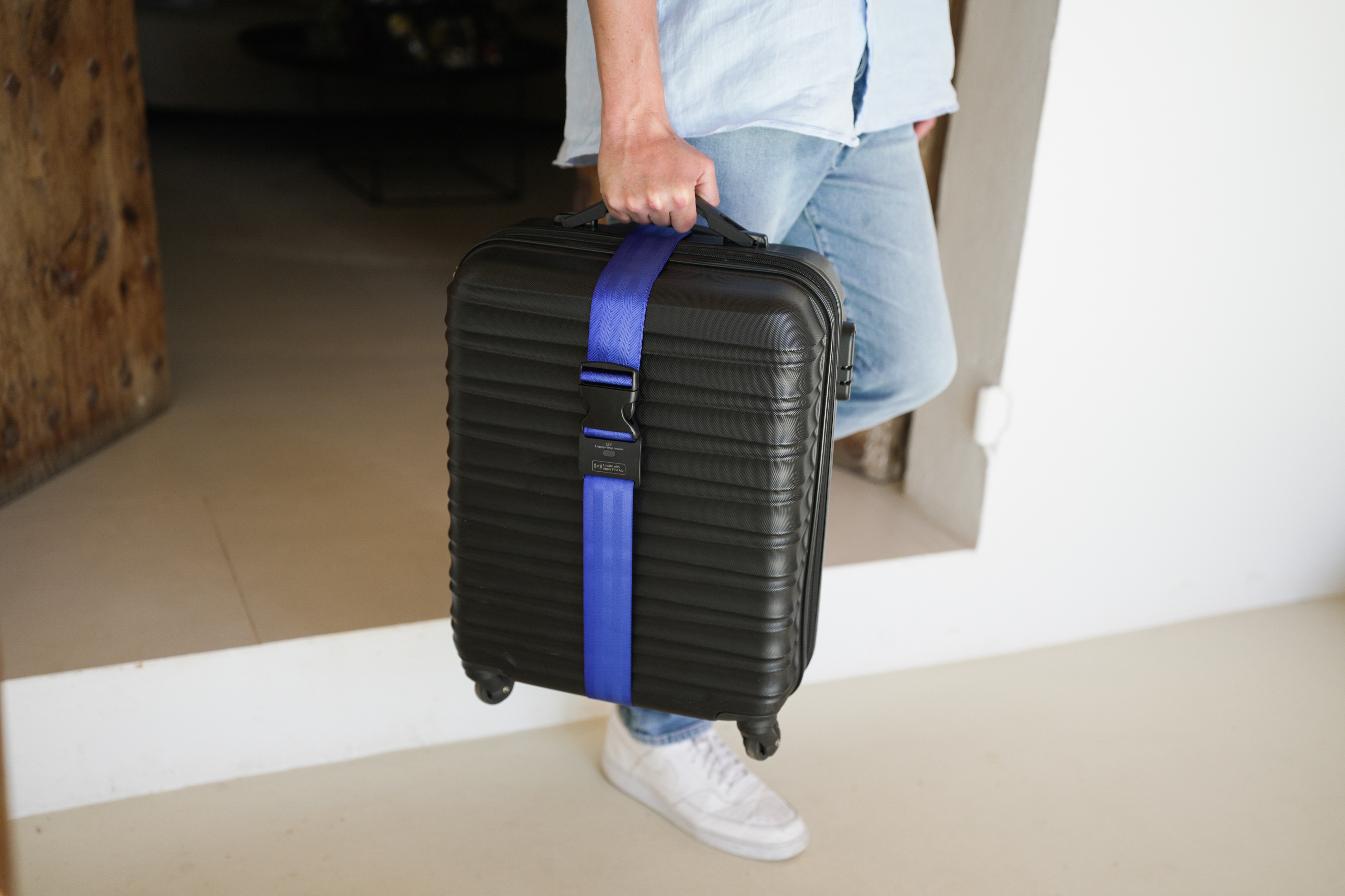 Person mit schwarzem Koffer mit blauem Gurt