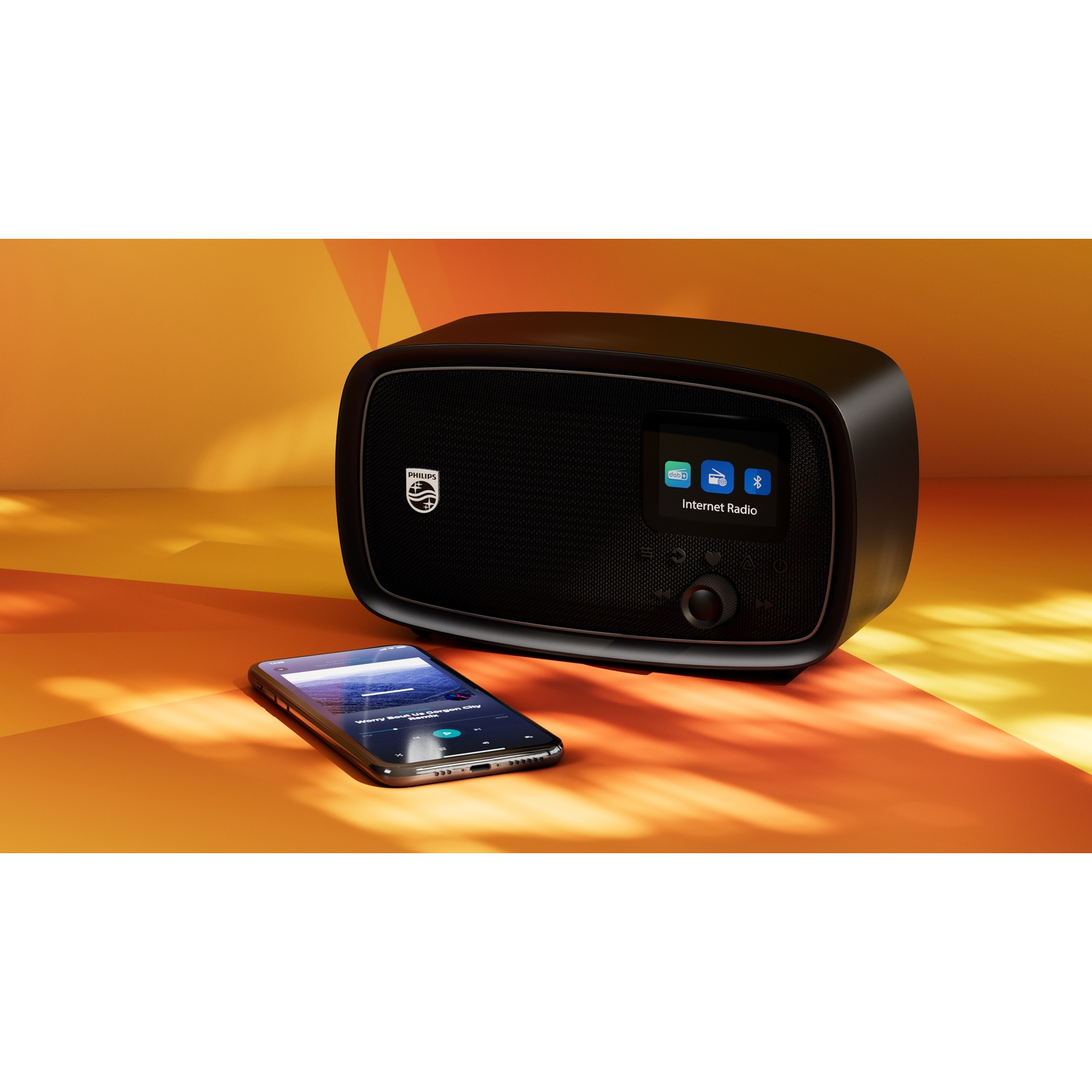 Una radio internet Philips nera e uno smartphone su una superficie arancione-gialla.