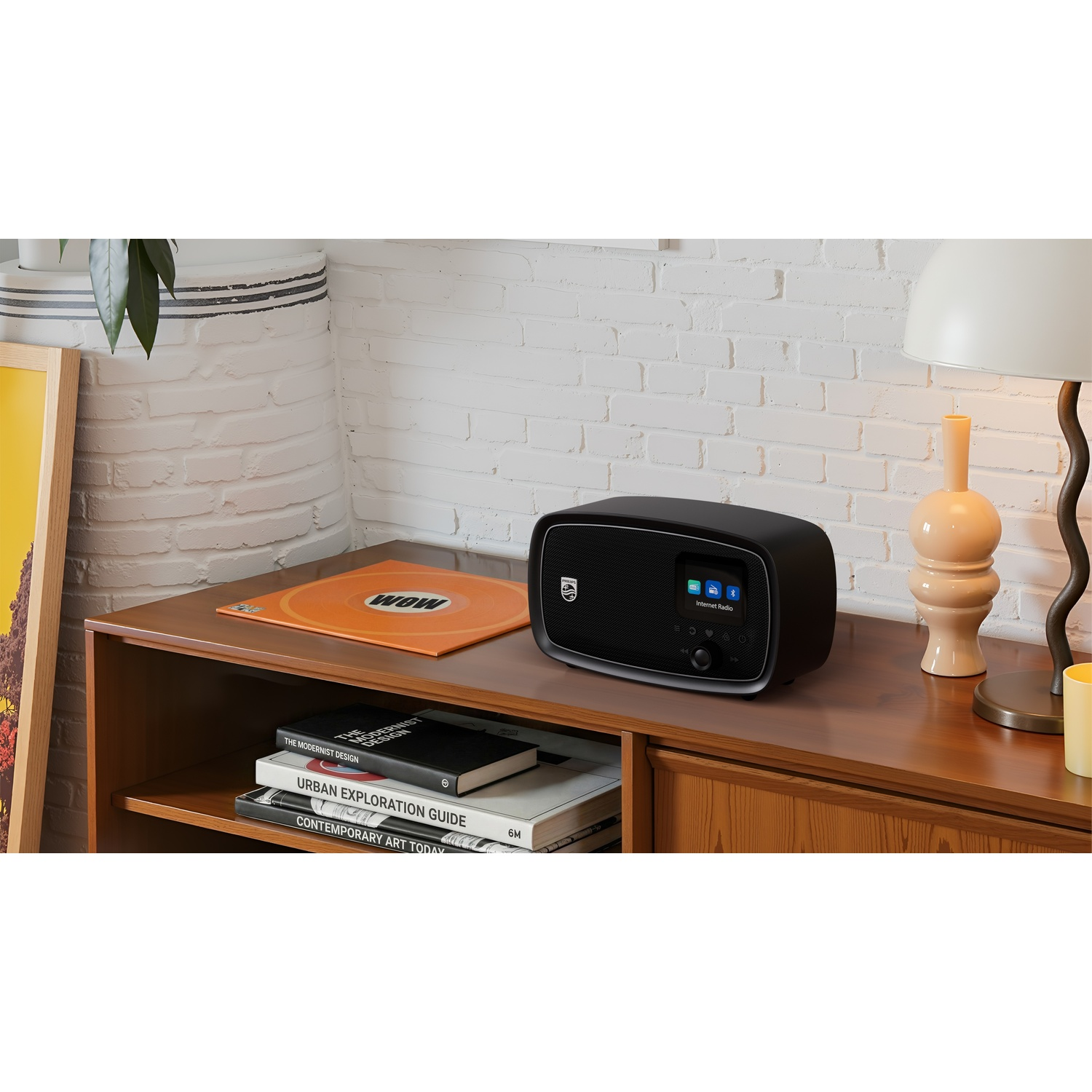 Una radio Internet Philips nera è su un mobile in legno accanto a un disco e libri.
