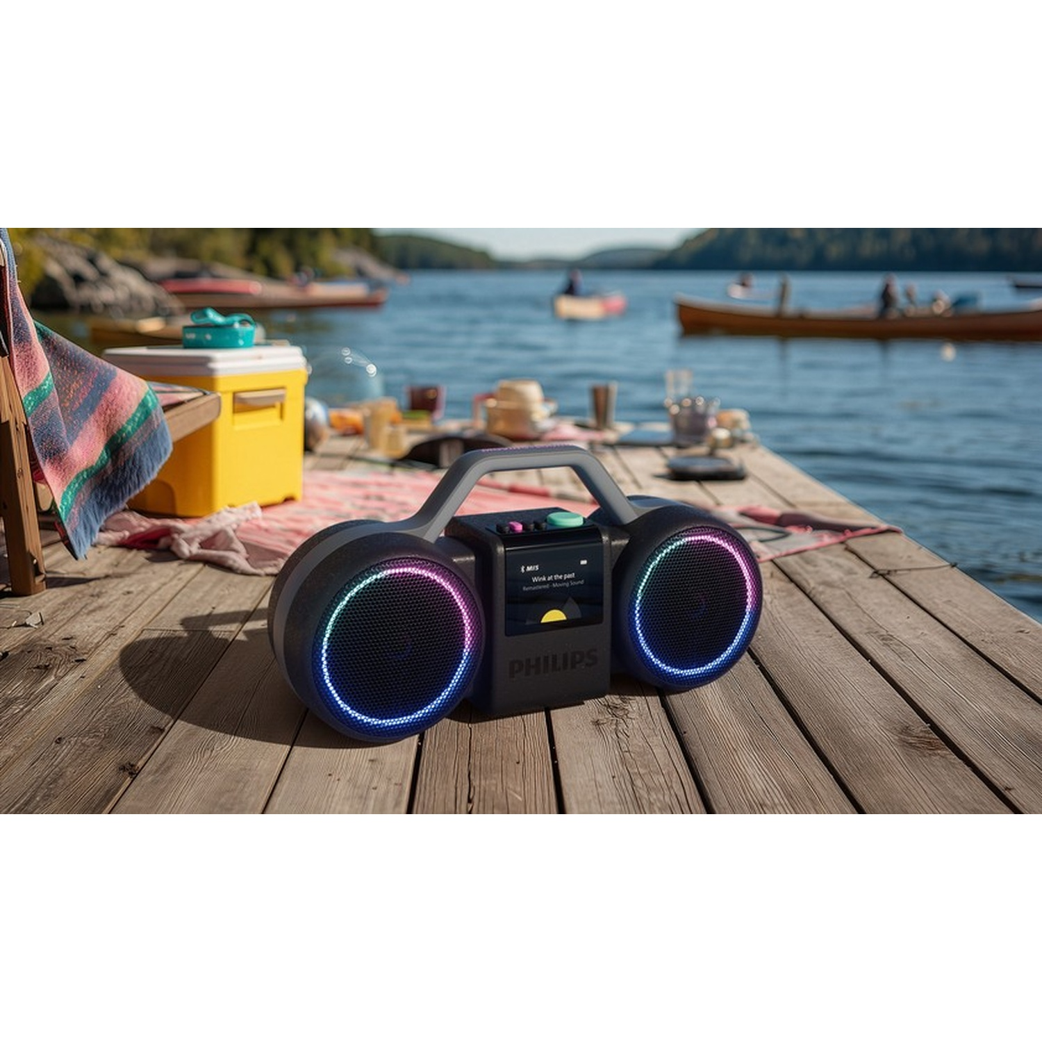 Un altoparlante portatile con luci colorate su un molo di legno vicino all'acqua.