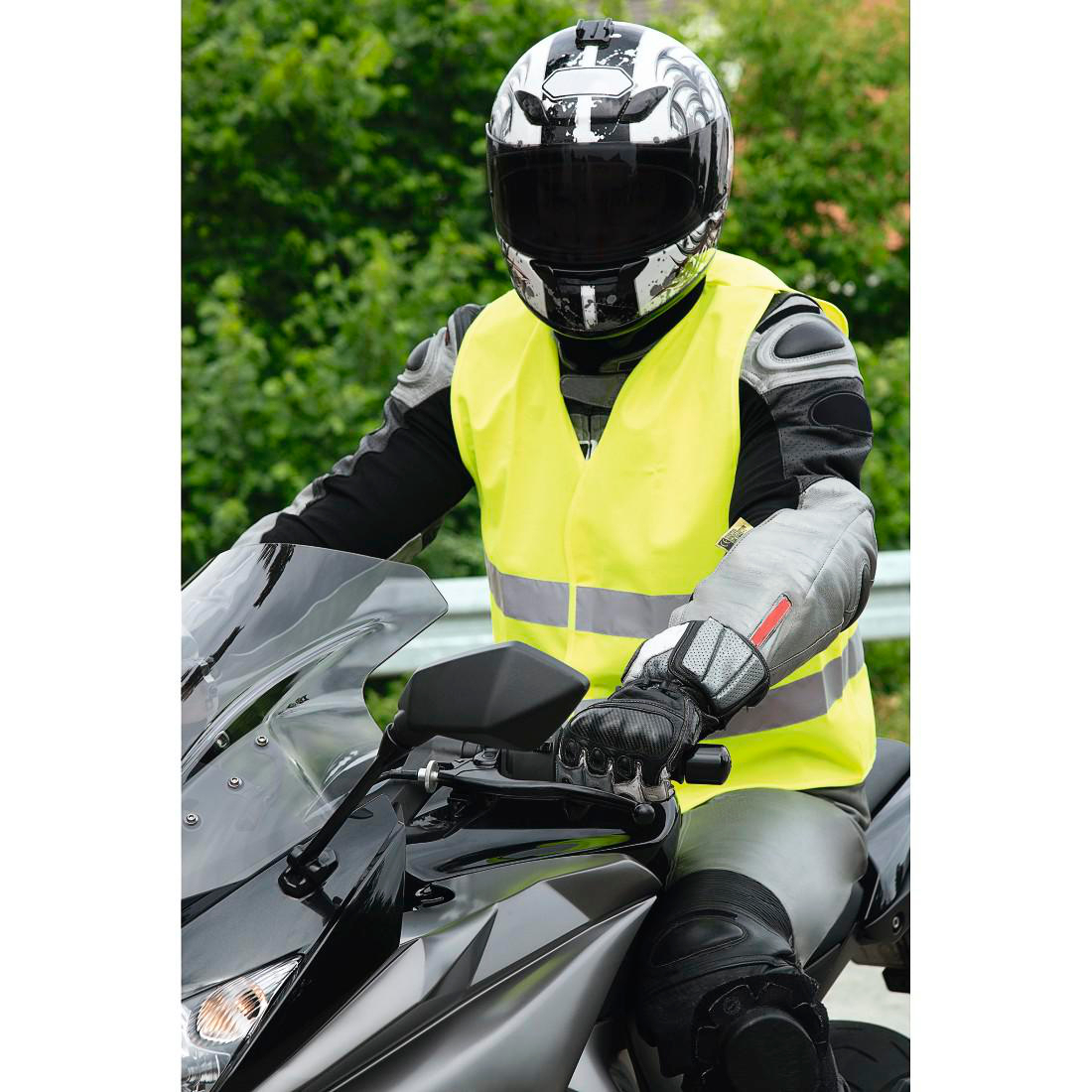 Motorradfahrer in gelber Warnweste und Helm fährt.