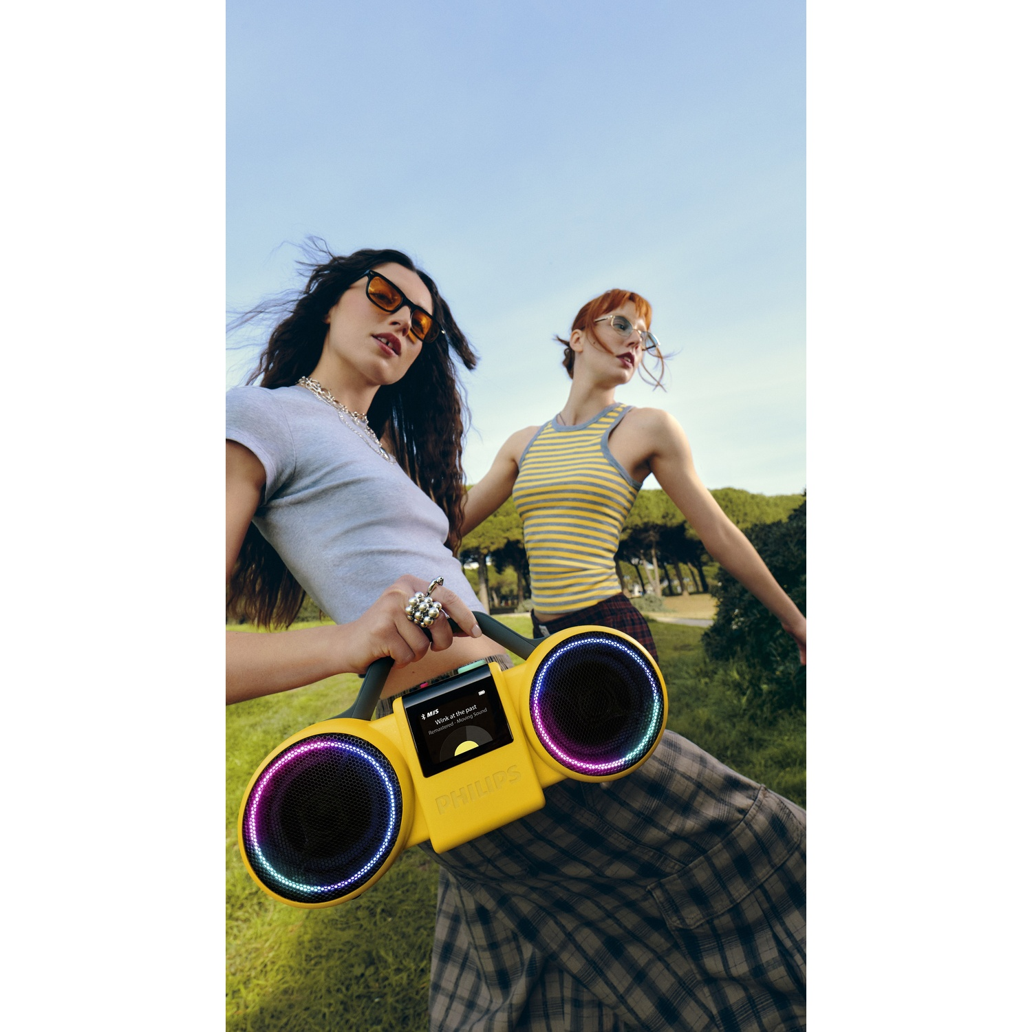 Due donne all'aperto con un altoparlante giallo dotato di luci colorate.