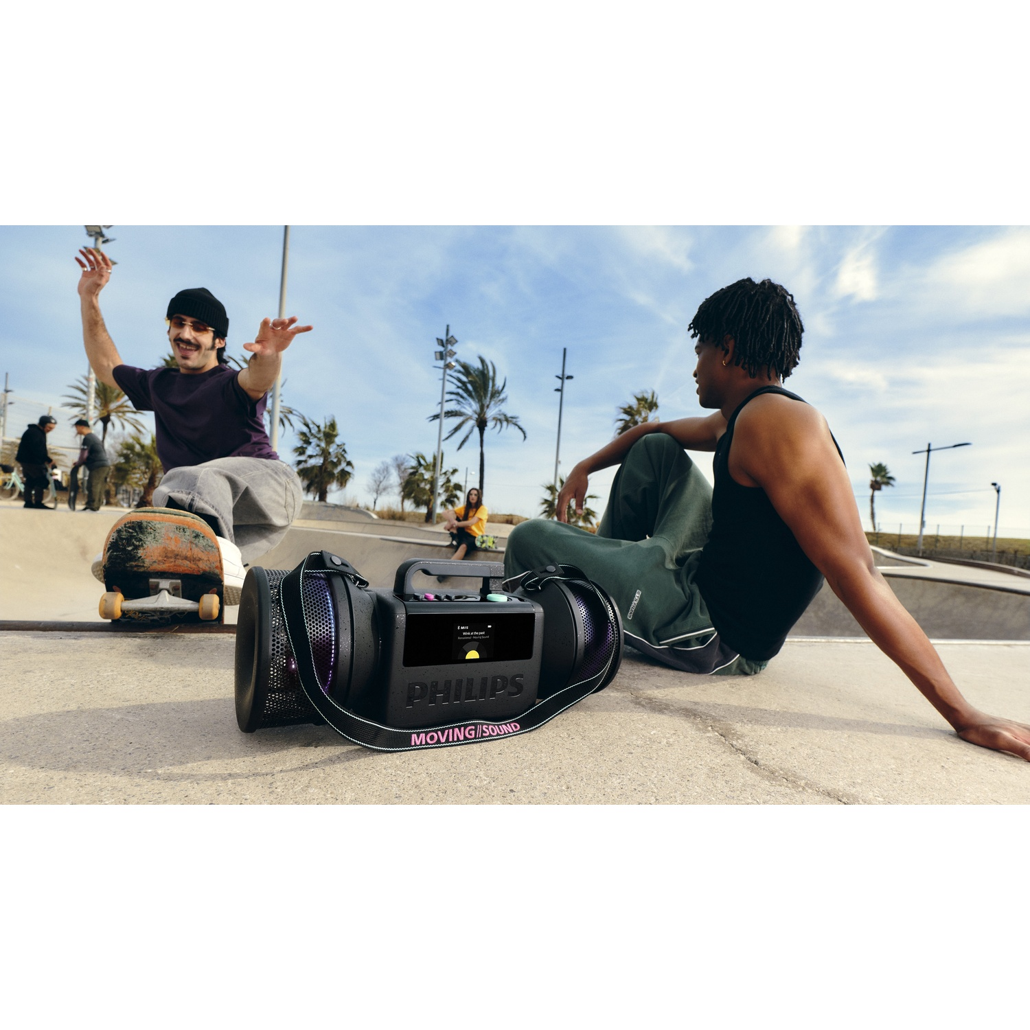 Due uomini in uno skatepark con uno speaker Philips. Uno fa skateboard, l'altro è seduto.