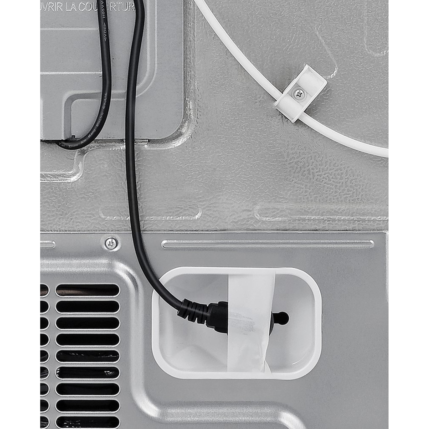Een zwarte kabel met stekker is bevestigd in een witte bak. Een witte kabel wordt vastgehouden door een clip.
