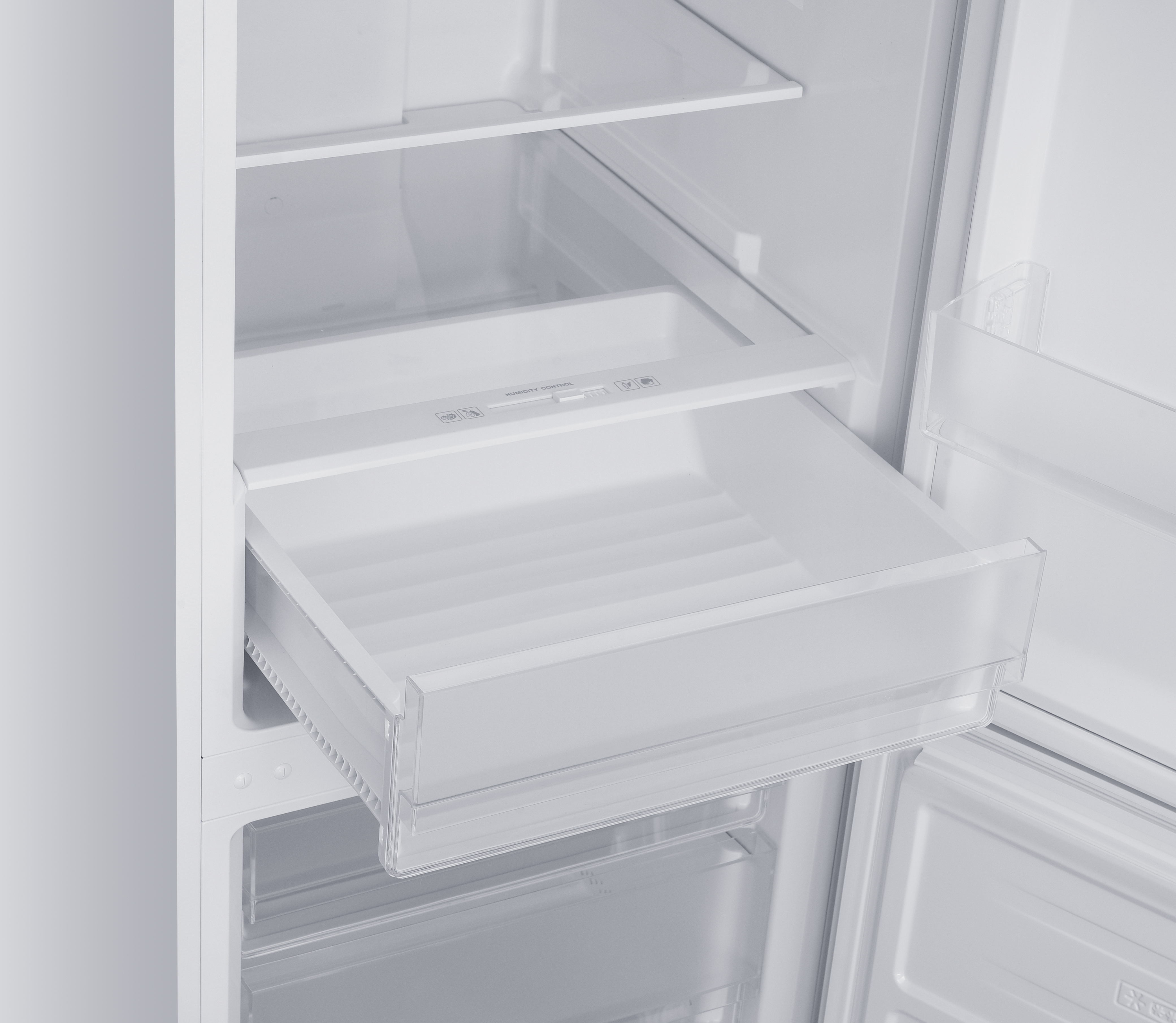 Vista interior de un refrigerador blanco con un cajón abierto.