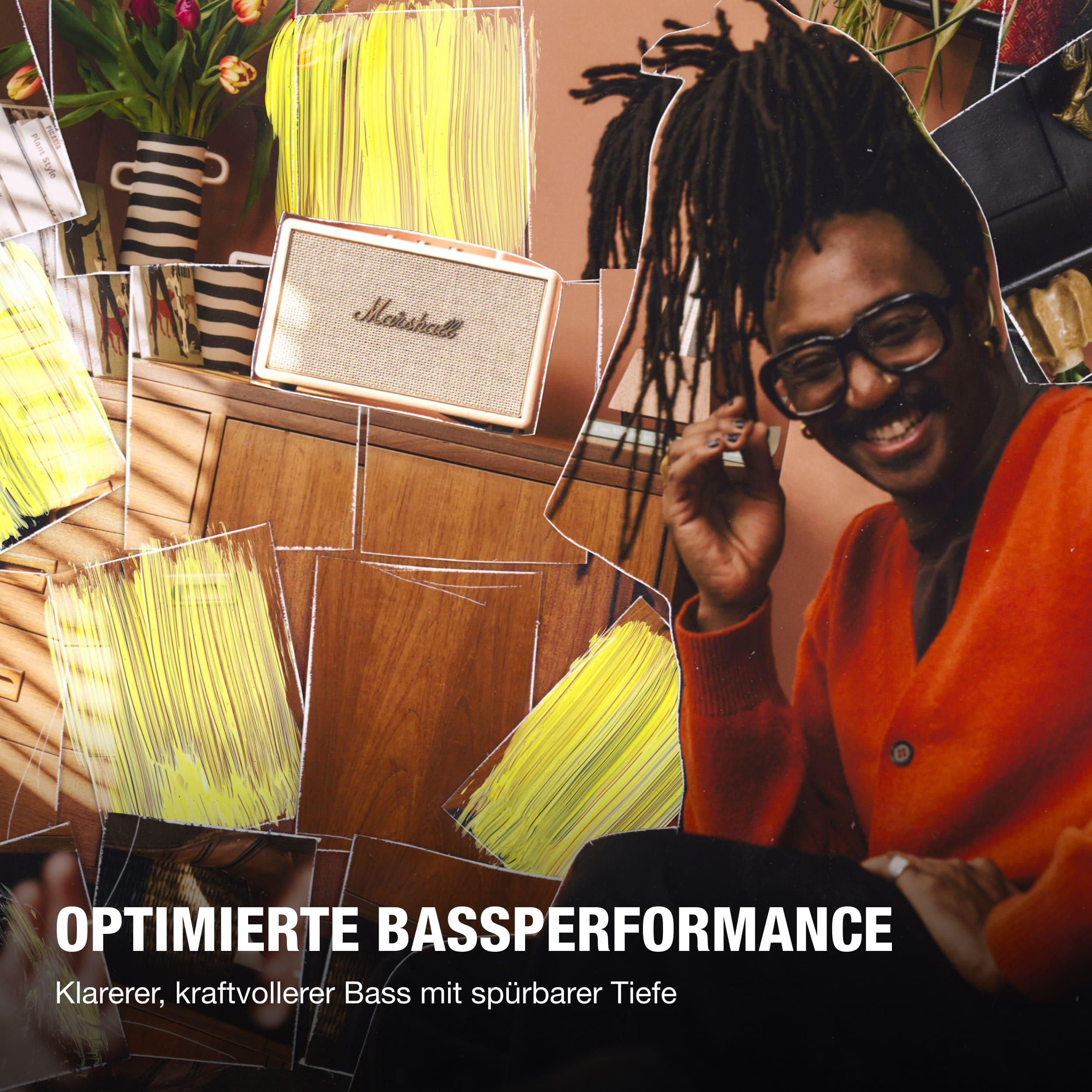 Mann mit Dreadlocks und Brille lächelt, trägt orangefarbene Strickjacke.