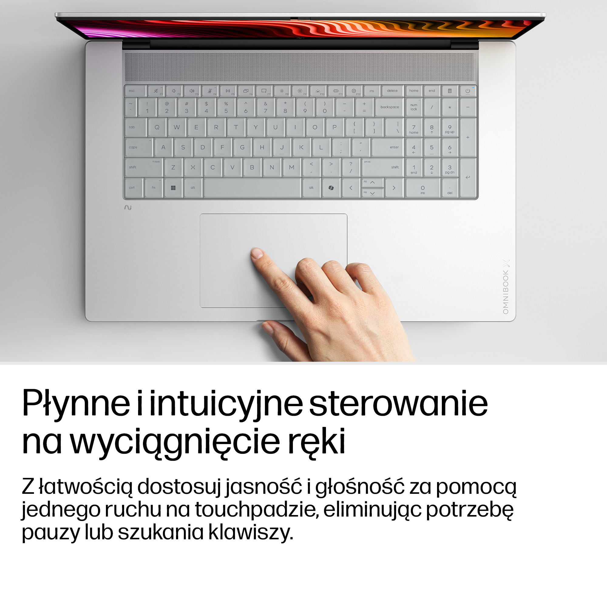 Dłoń obsługuje touchpad jasnoszarego laptopa z podświetlaną klawiaturą.