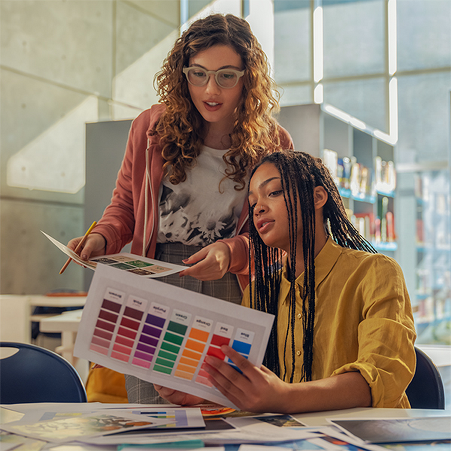 Dos mujeres miran muestras de color en una sala luminosa.