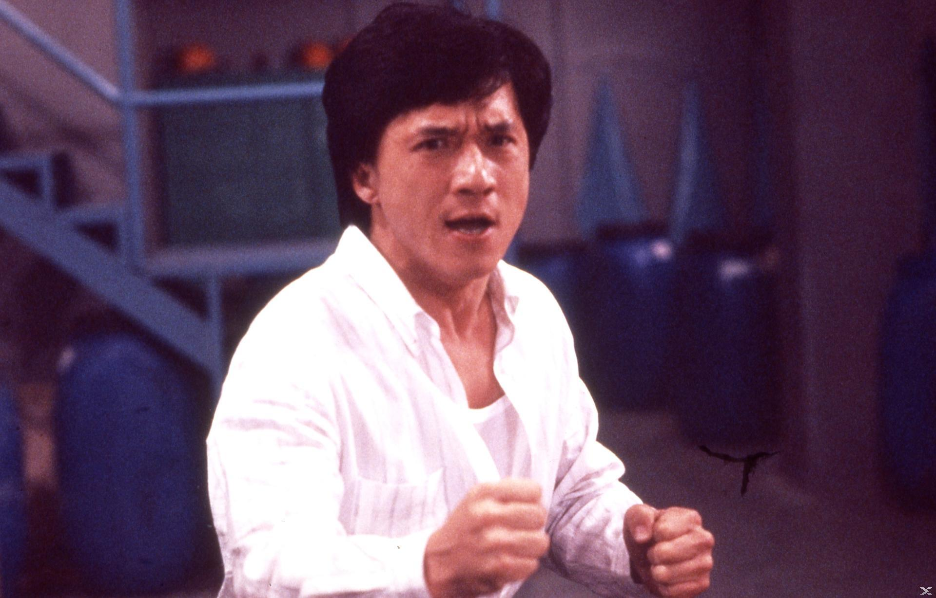 Jackie Chan in weiem Hemd mit Füusten geballt, entschlossen.