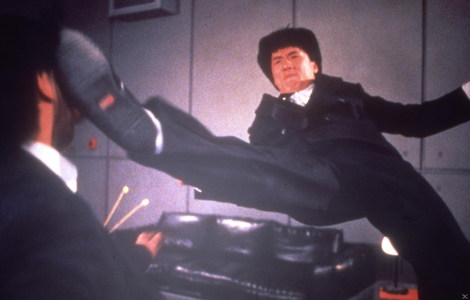 Jackie Chan führt einen Tritt in der Luft aus, während ein Gegner ihm gegenübersteht.