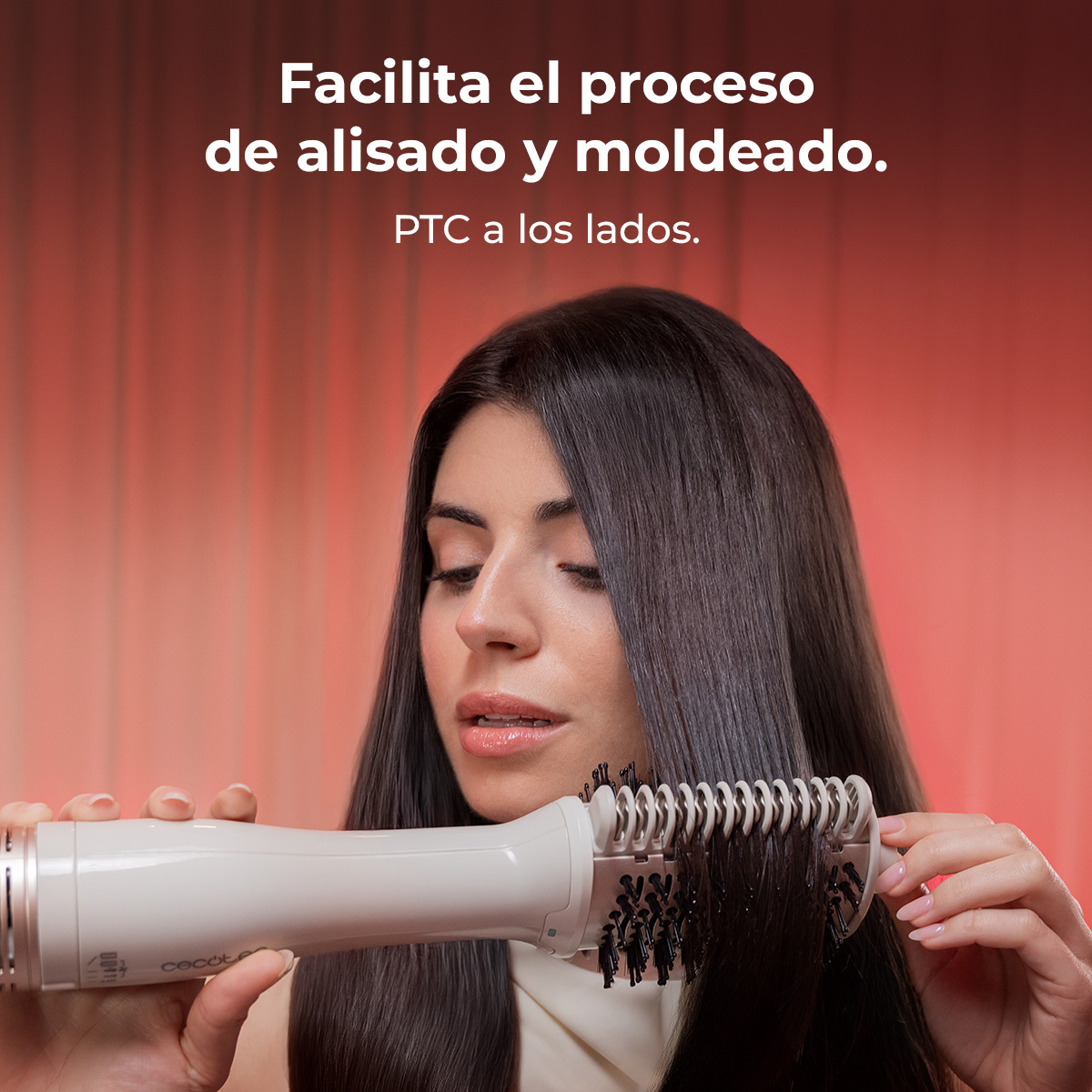 Una mujer se alisa el pelo largo y oscuro con un cepillo secador blanco.