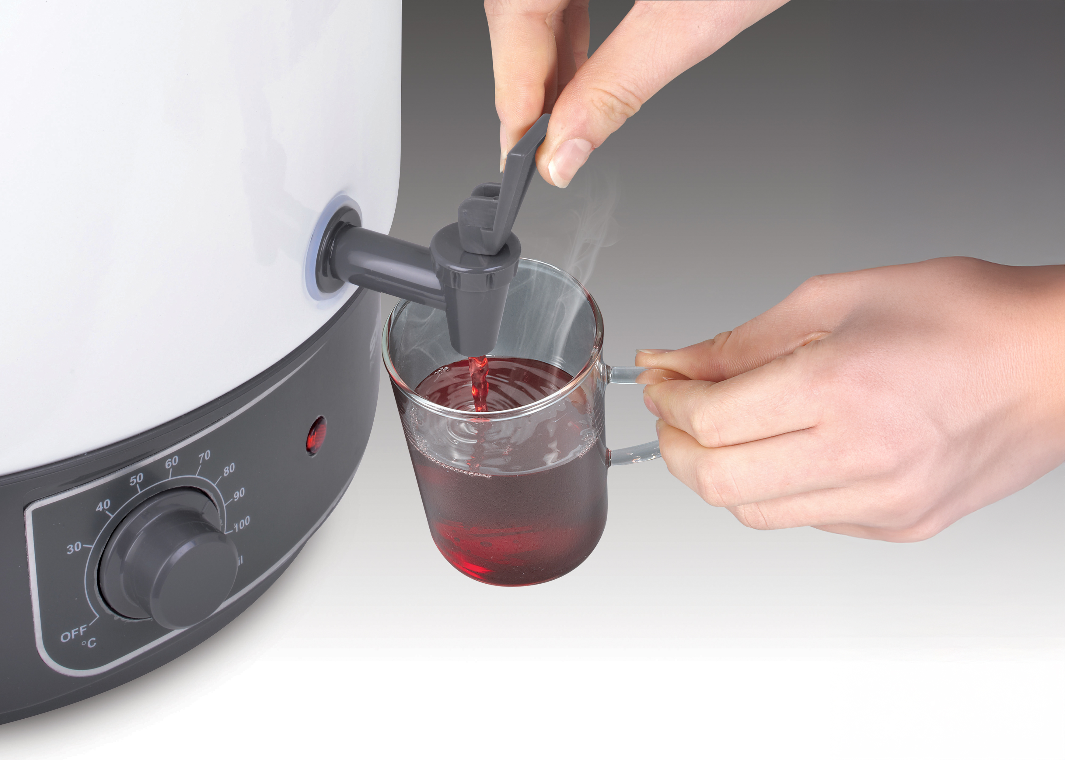 Heißes Getränk fließt aus einem Spender in eine Glas Tasse.