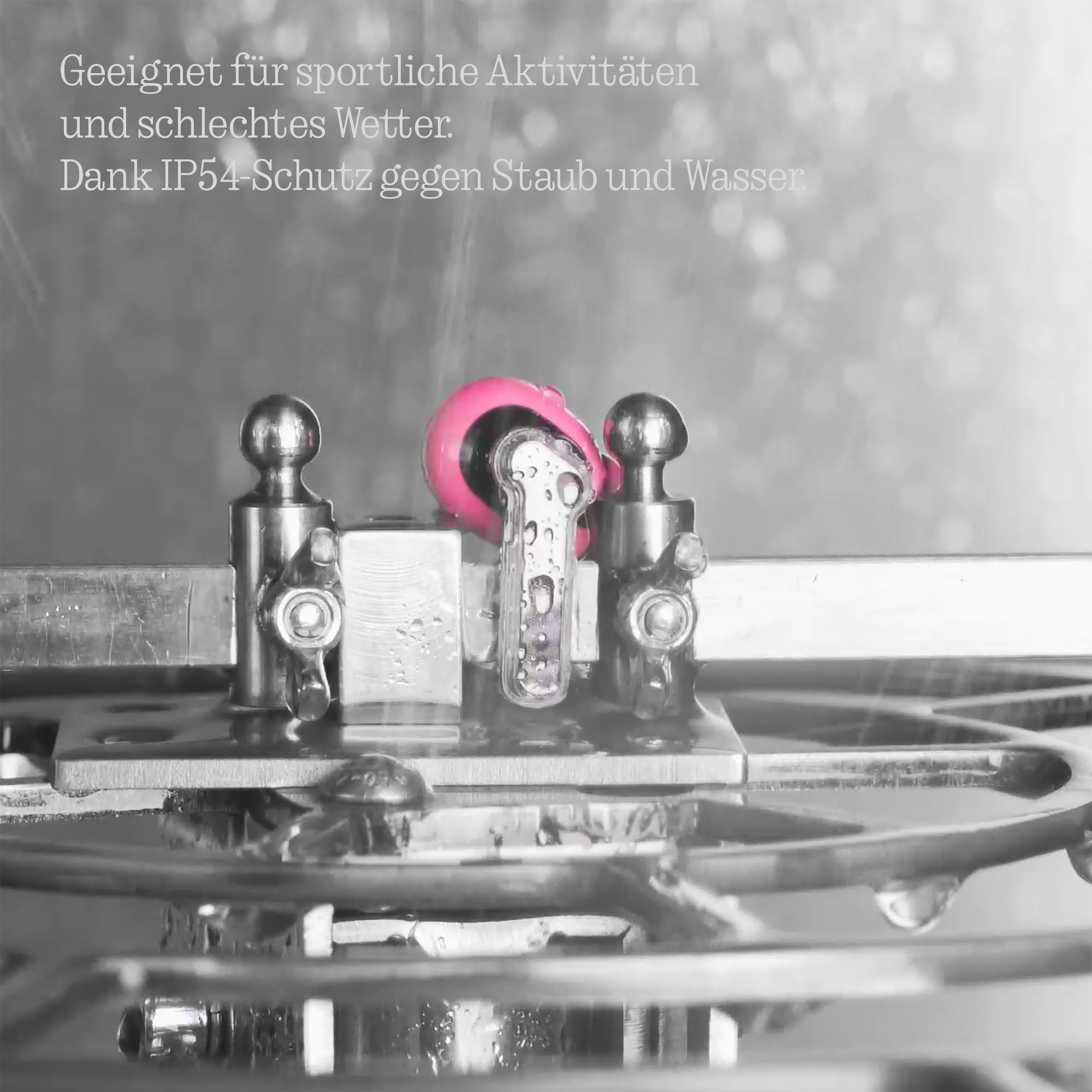 Detailaufnahme eines Metallmechanismus mit einem pinken Rad, nass.