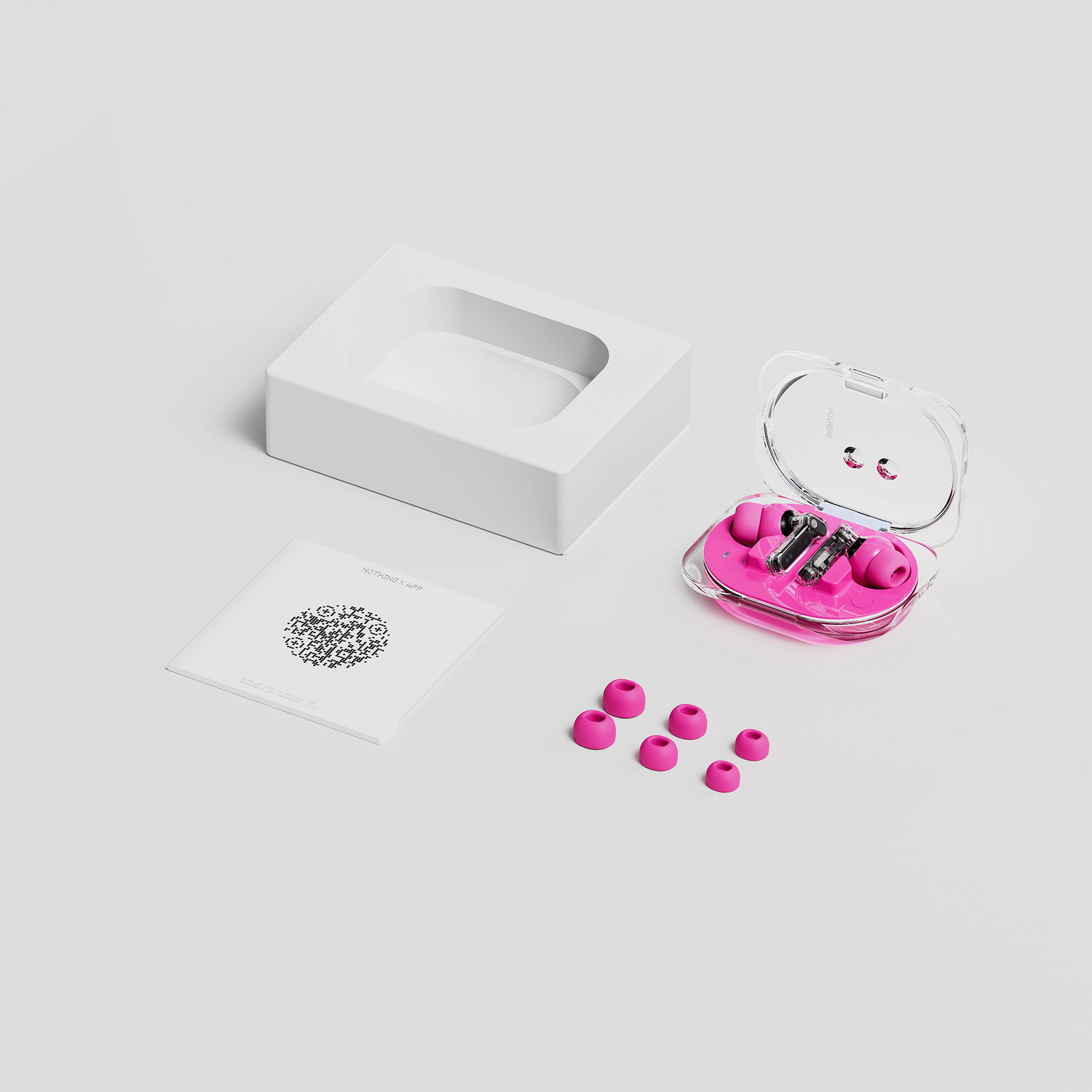 Auriculares rosas en estuche transparente con puntas extra y manual, sobre superficie blanca.