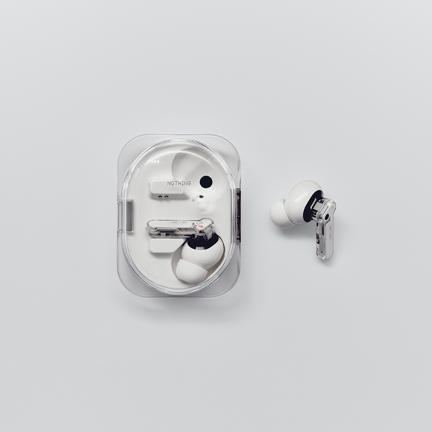 Auriculares inalámbricos blancos dentro y fuera de un estuche transparente sobre fondo blanco.