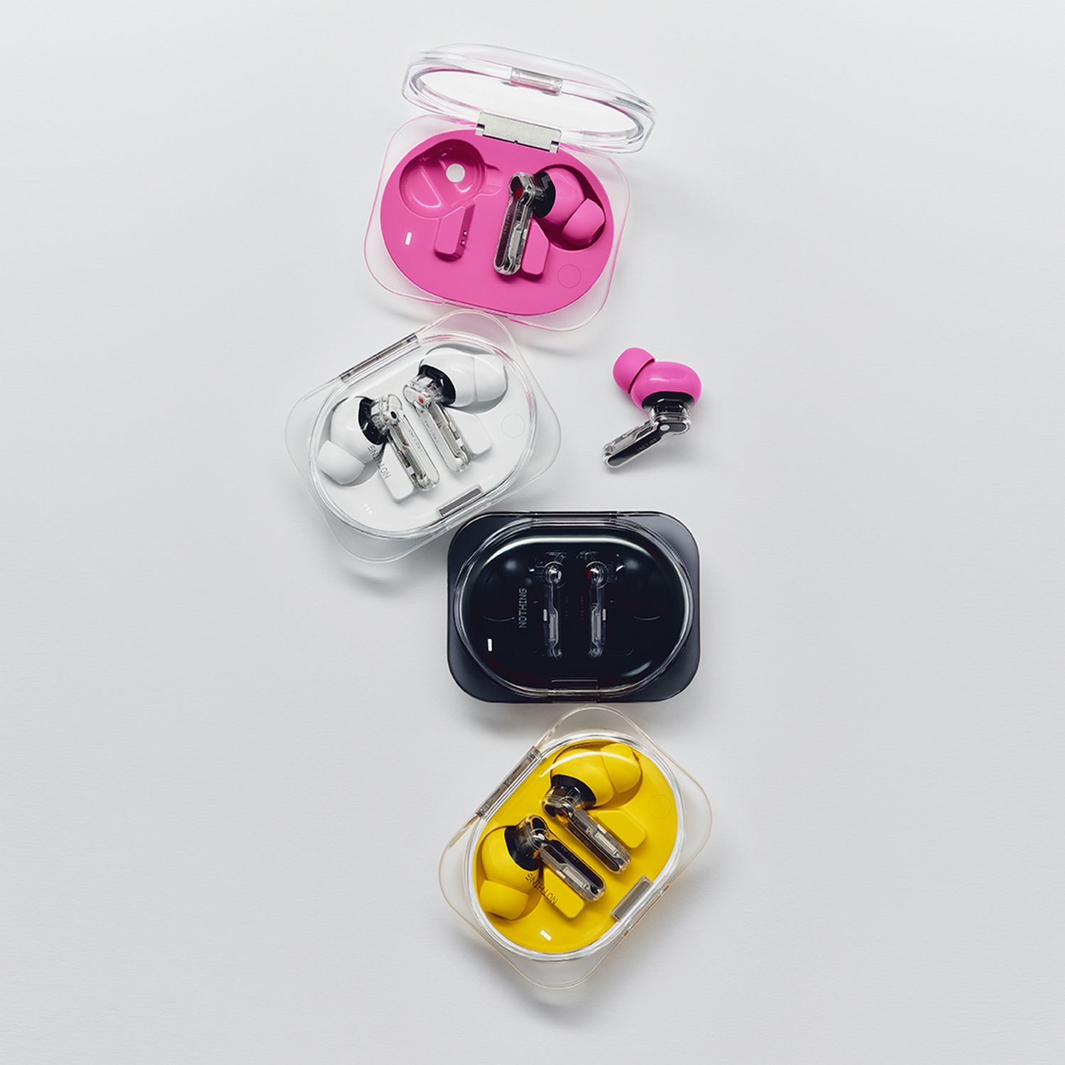 Cuatro estuches transparentes con auriculares inalámbricos en rosa, blanco, negro y amarillo.