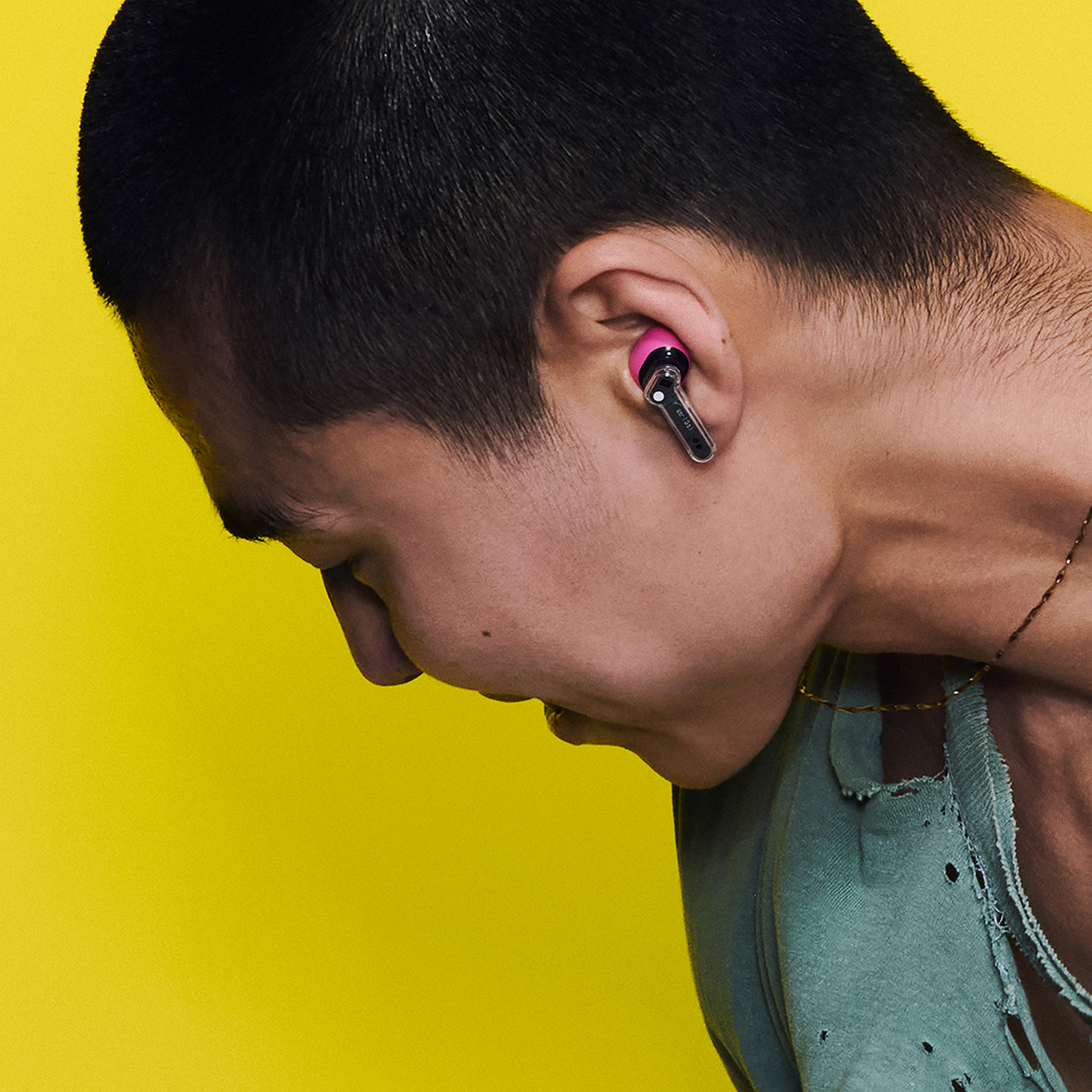 Hombre con auricular rosa en la oreja sobre fondo amarillo.