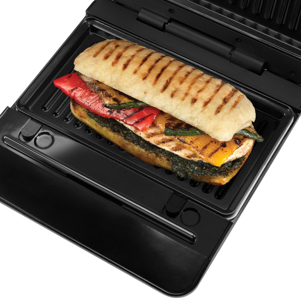 Kanapka typu panini z grillowanymi warzywami i kurczakiem piecze się na czarnej grillownicy.