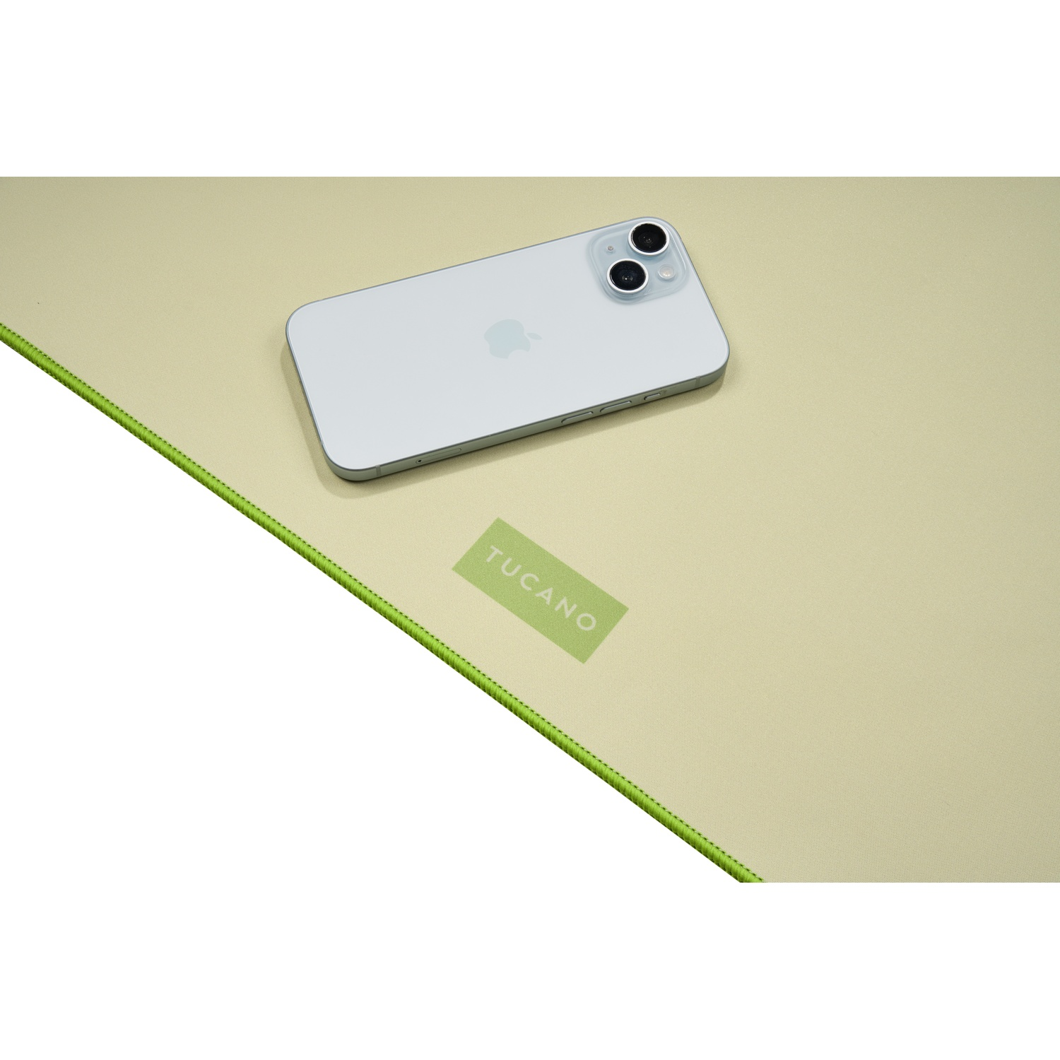 Un iPhone argentato poggia su un tappetino beige chiaro con bordo verde.