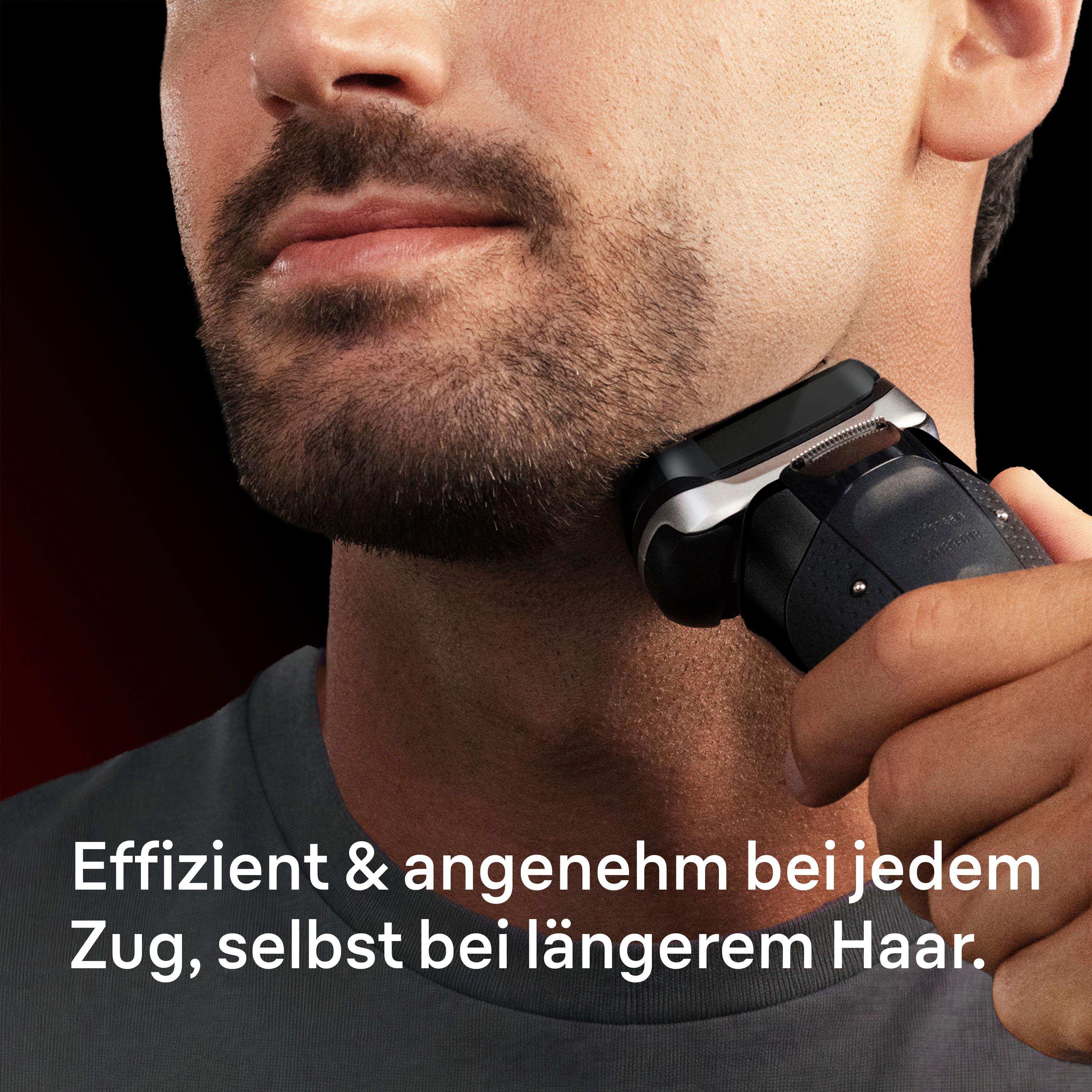 Mann rasiert sich mit elektrischem Rasierer im Gesicht. Schwarzer Hintergrund.
