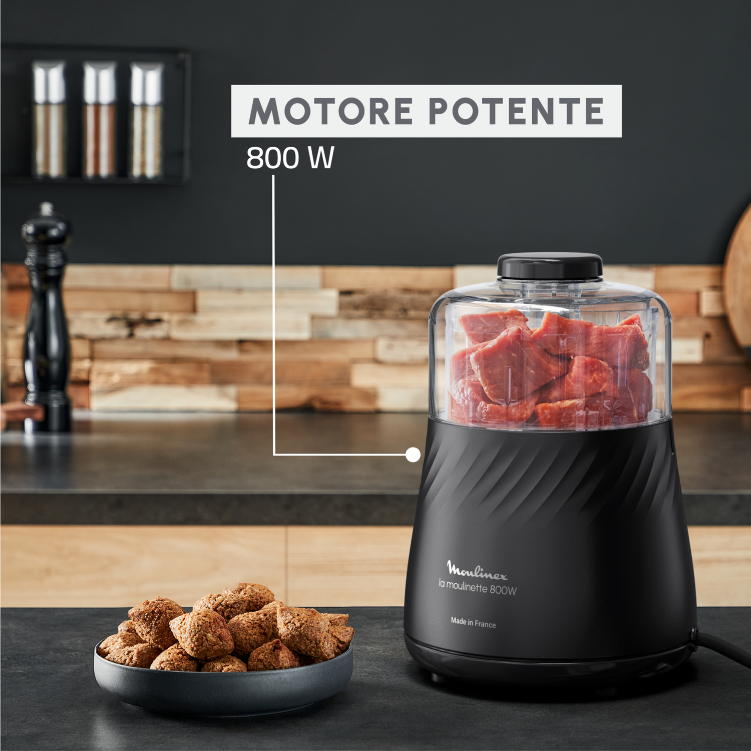 Robot da cucina nero con carne cruda, accanto a una ciotola di biscotti.