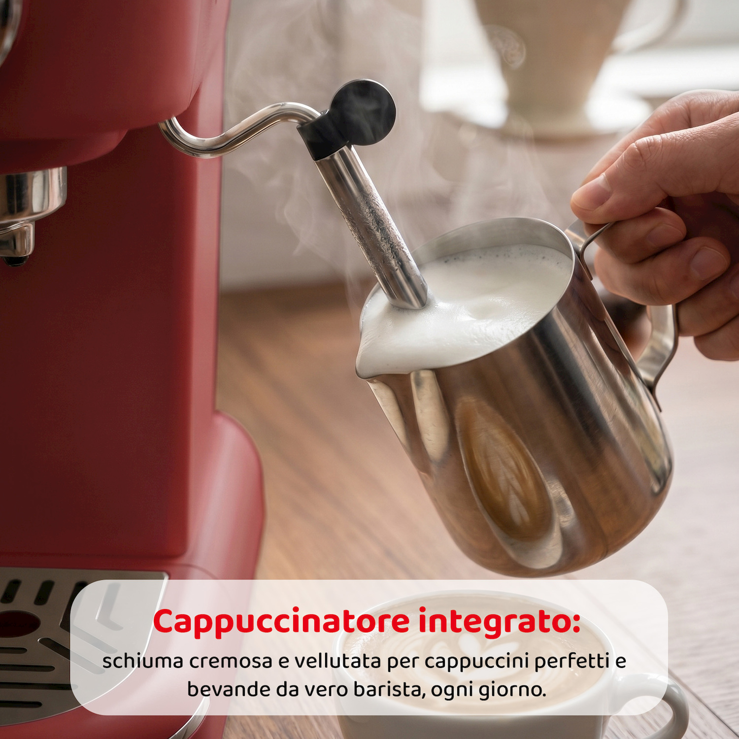 Una mano monta il latte in una caraffa di metallo con una macchina del caffè rossa.