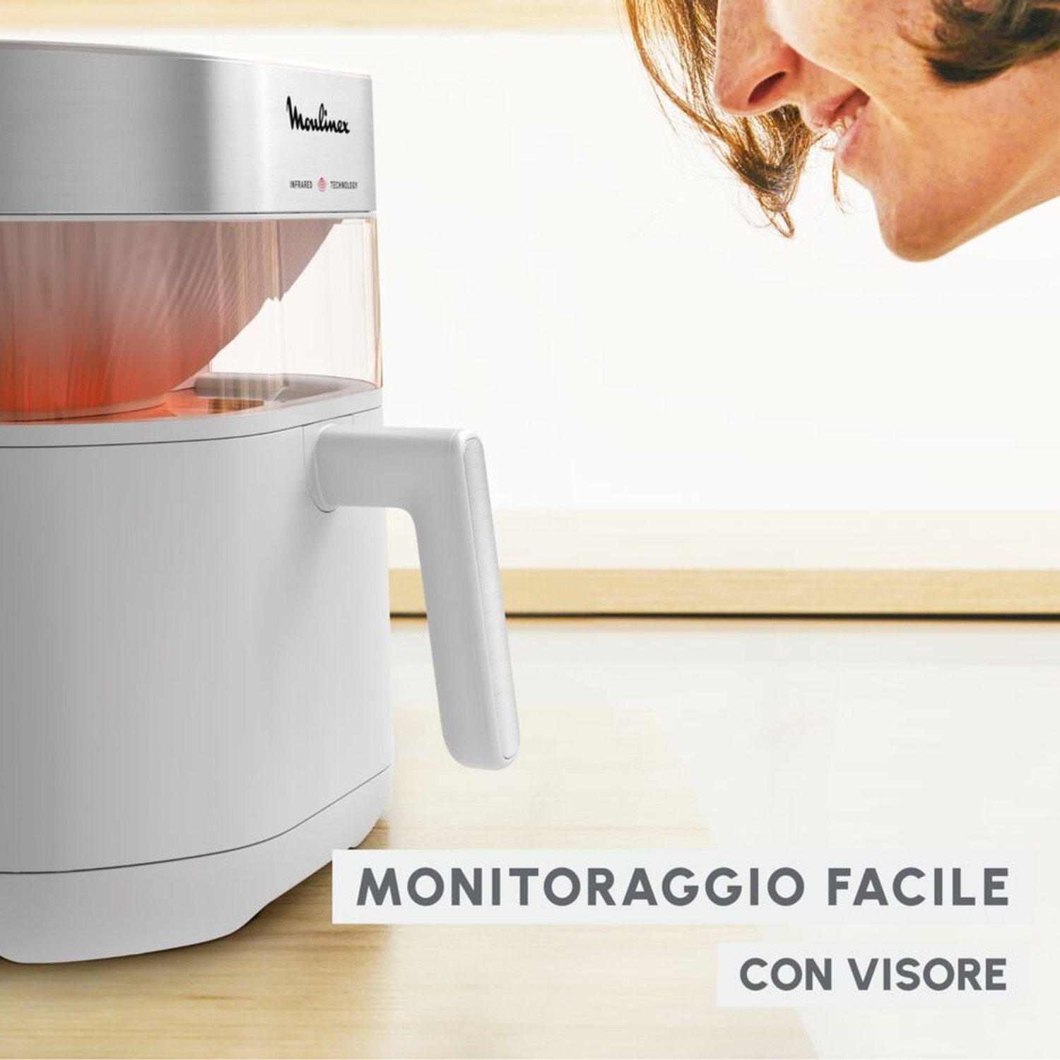 Elettrodomestico bianco con contenitore trasparente e calore rosso. Una persona guarda.