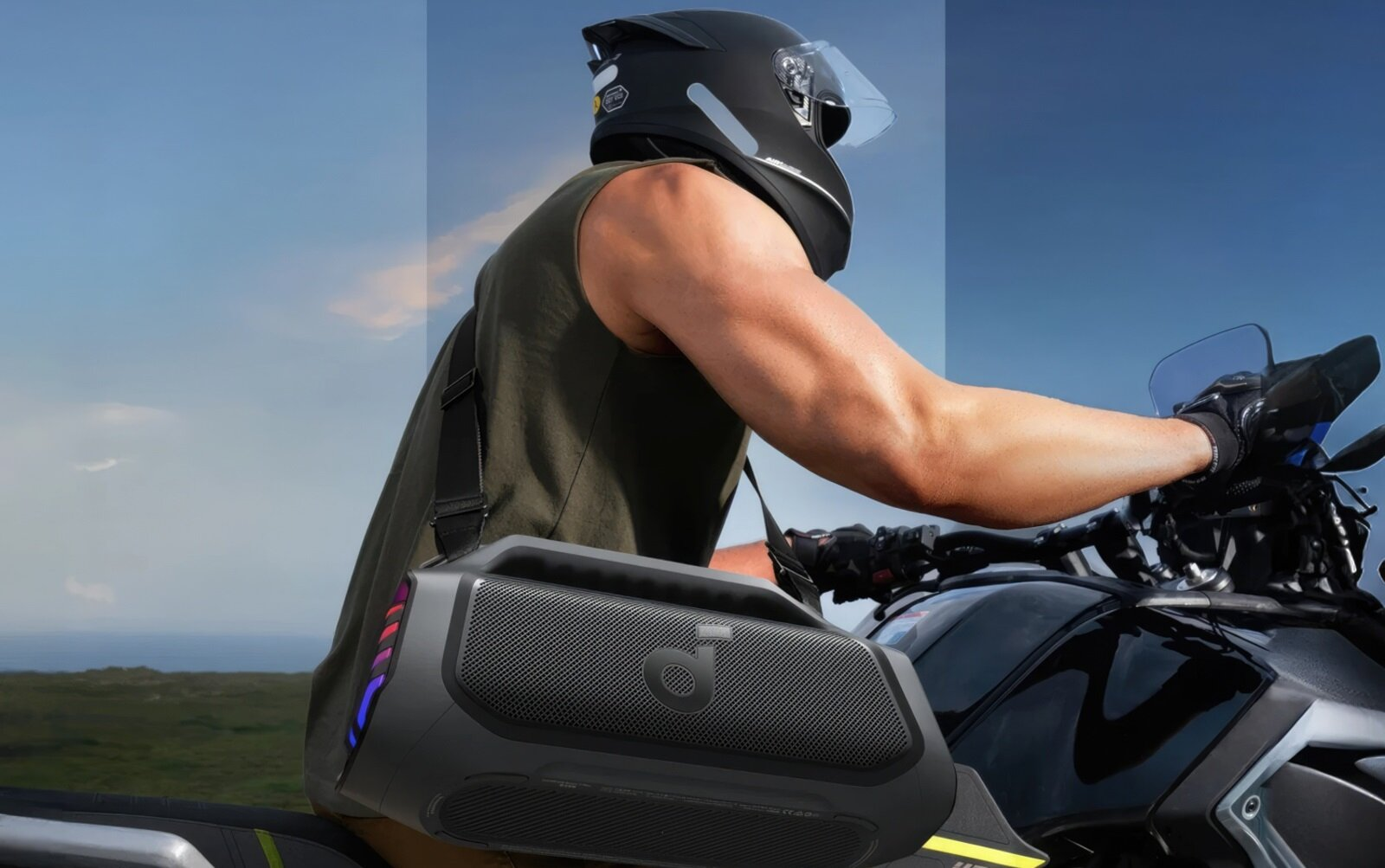 Mężczyzna w kasku jedzie motocyklem, niesie torbę głośnikową.