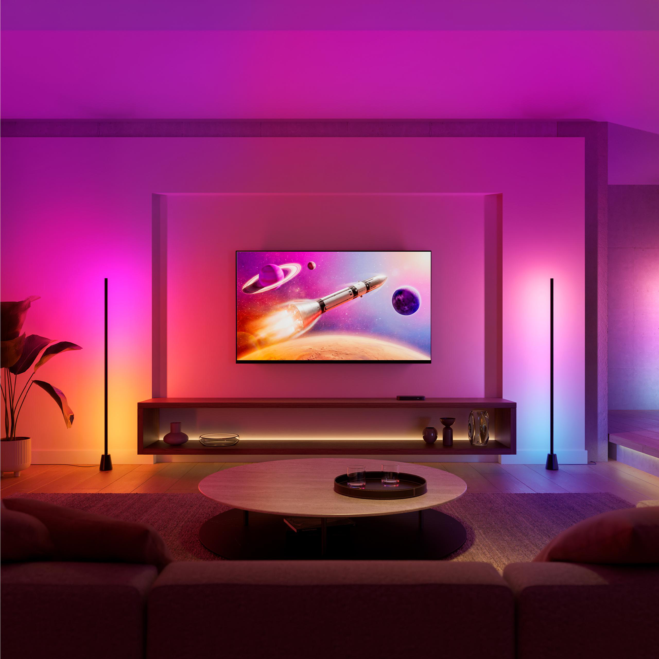 Ein Wohnzimmer mit einem Fernseher, der einen Raketenstart zeigt. Bunte Beleuchtung.