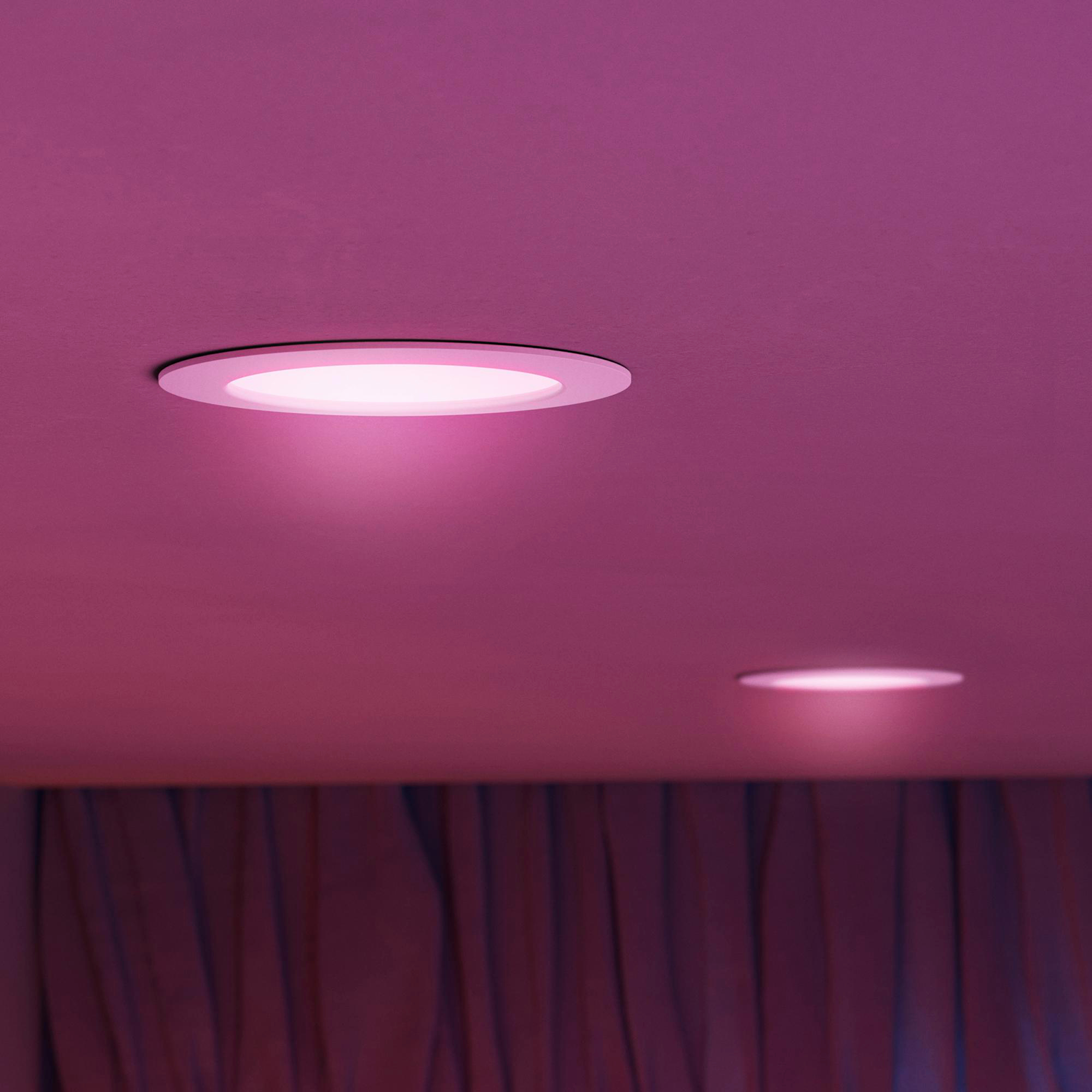 Zwei runde Deckenleuchten werfen pinkes Licht auf eine pinke Decke.