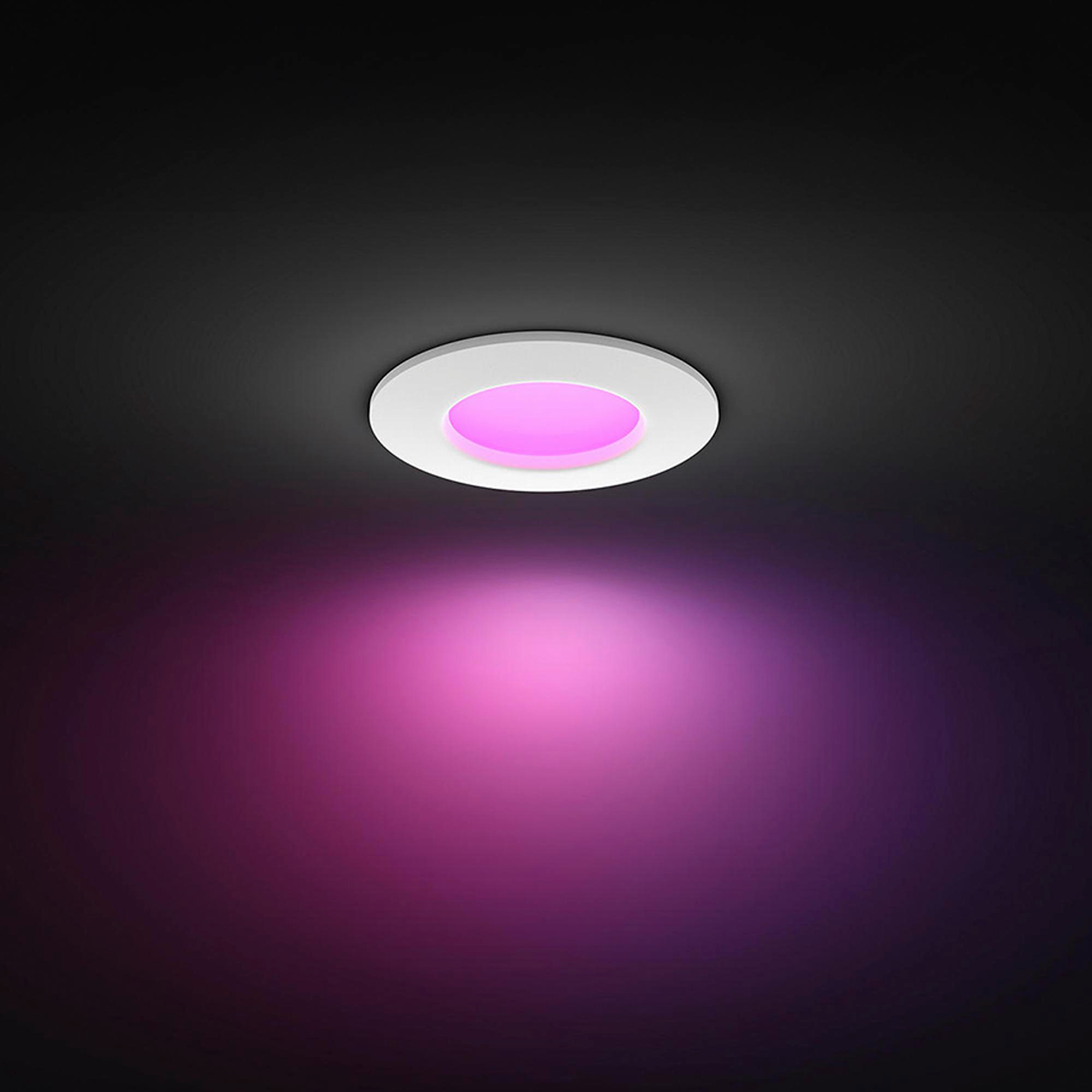 Ein runder Einbaustrahler strahlt pinkes Licht auf eine dunkle Fläche.