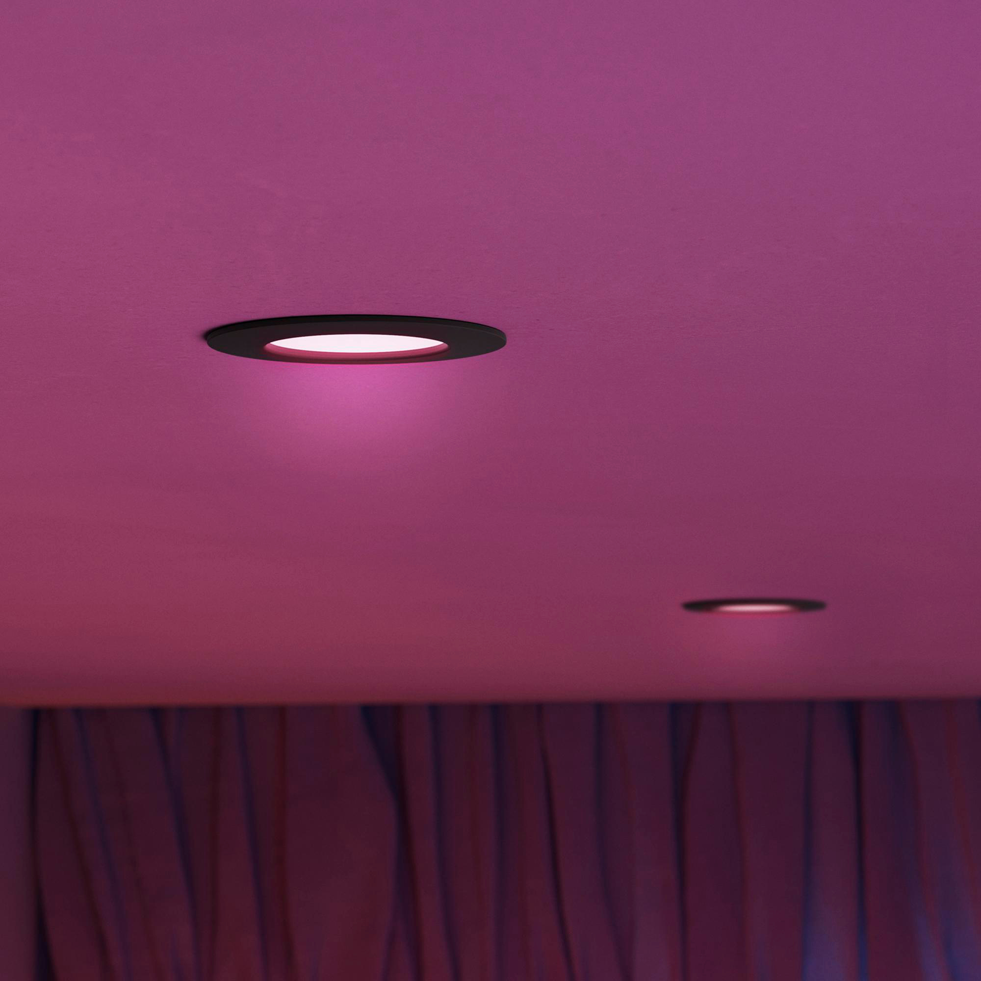 Zwei Einbaustrahler beleuchten eine pinke Decke über violetten Vorhängen.
