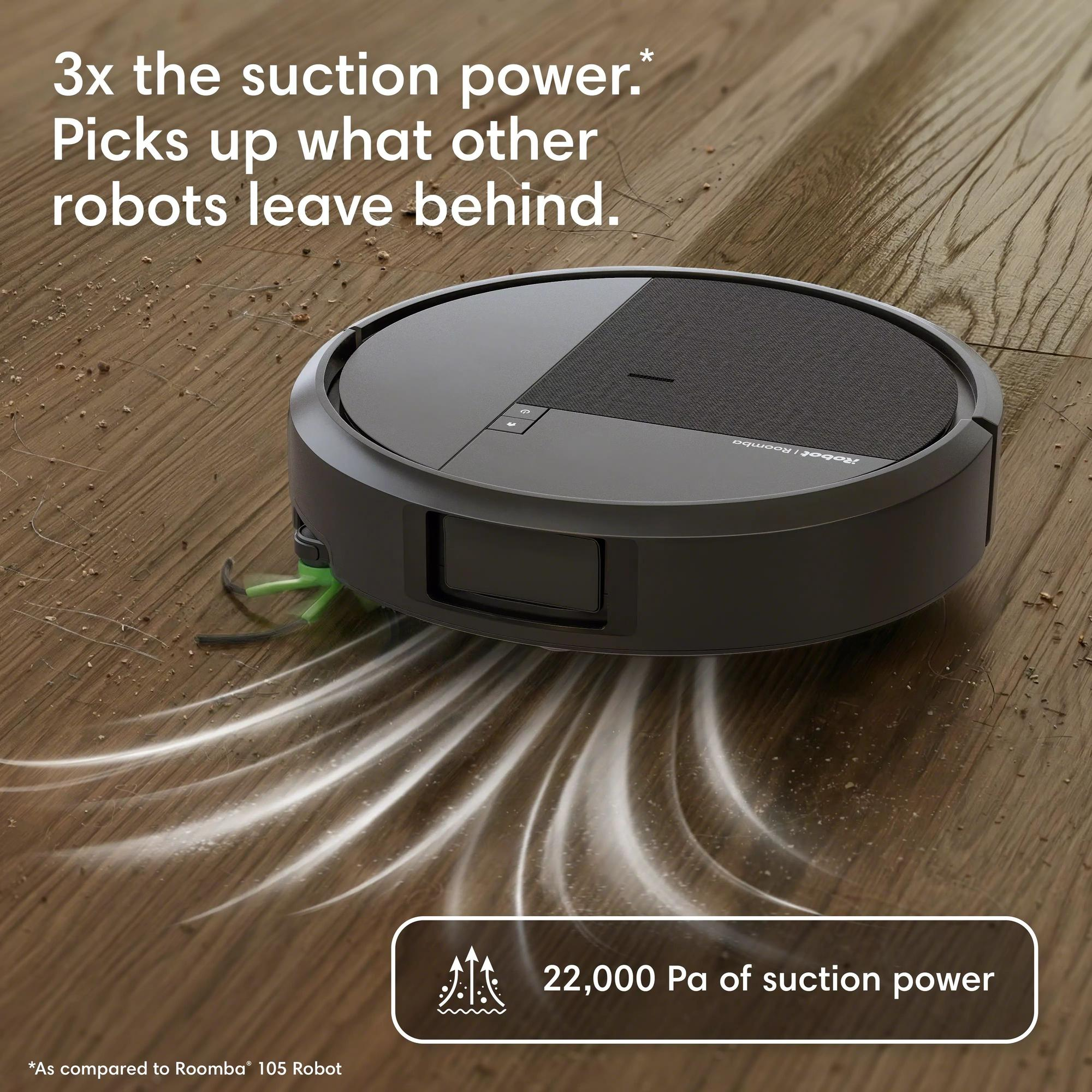 Un robot aspirateur gris foncé nettoie un parquet, laissant des traînées d'aspiration blanches.