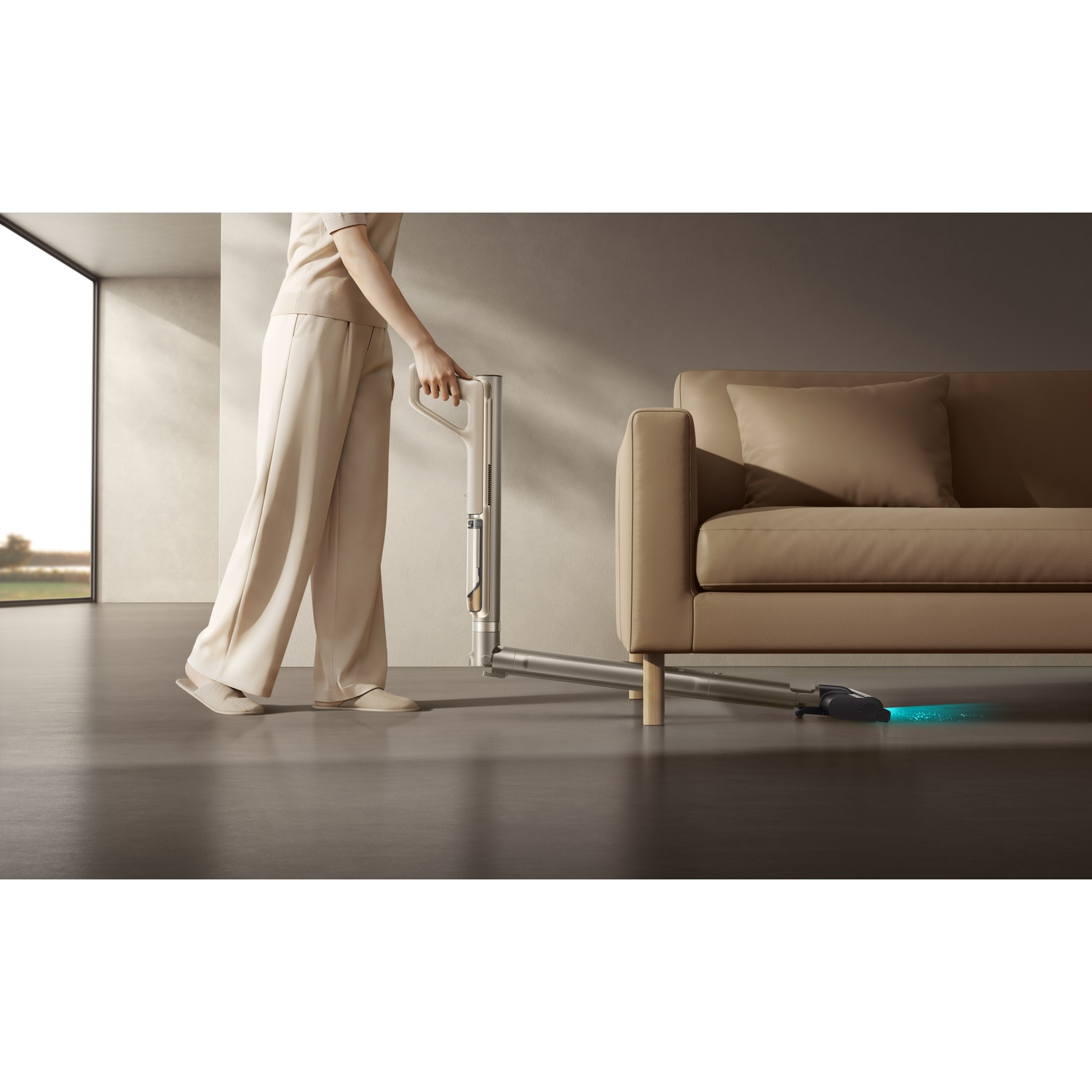 Persoon stofzuigt onder een beige bank met blauw lichteffect.