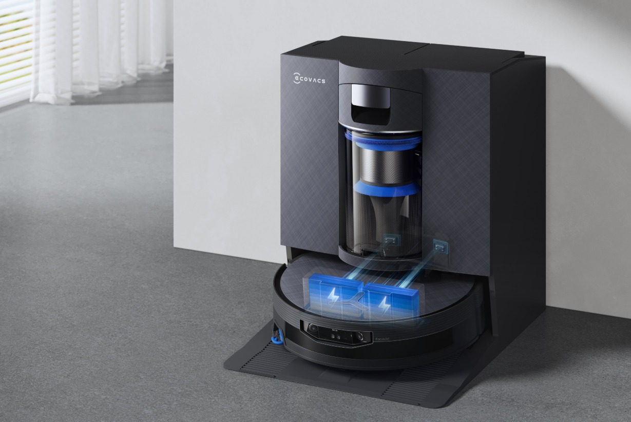 Robot odkurzający Ecovacs w ciemnej stacji ładującej z niebieskimi ikonami baterii.